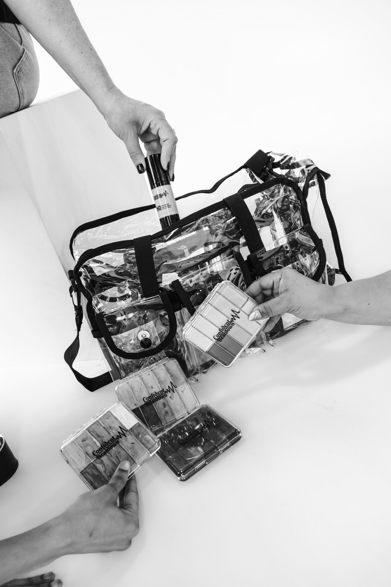 Three people handle a transparent bag with test tubes and boxes on a white surface.