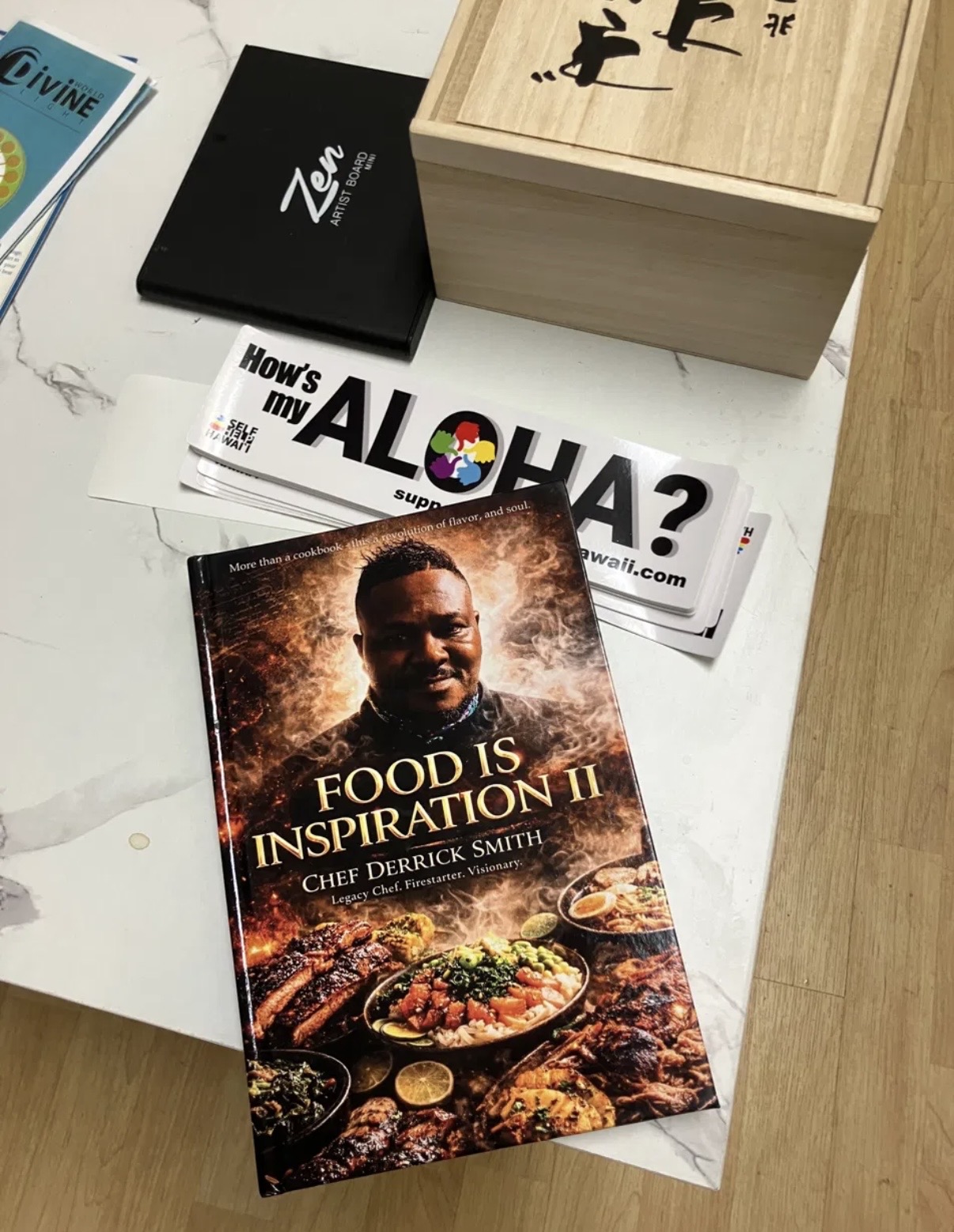 Book titled 'Food is Inspiration II' featuring a man with food dishes on cover, placed on a white surface.