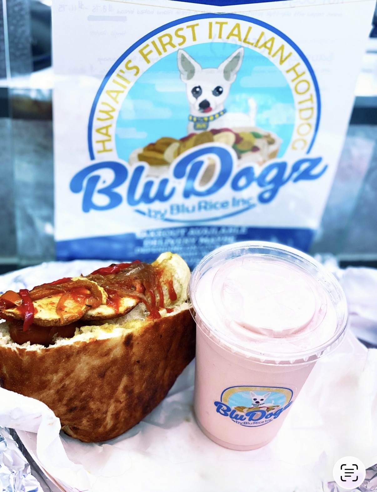 Sandwich, pink yogurt, and a sign with a dog illustration and text, on a table.