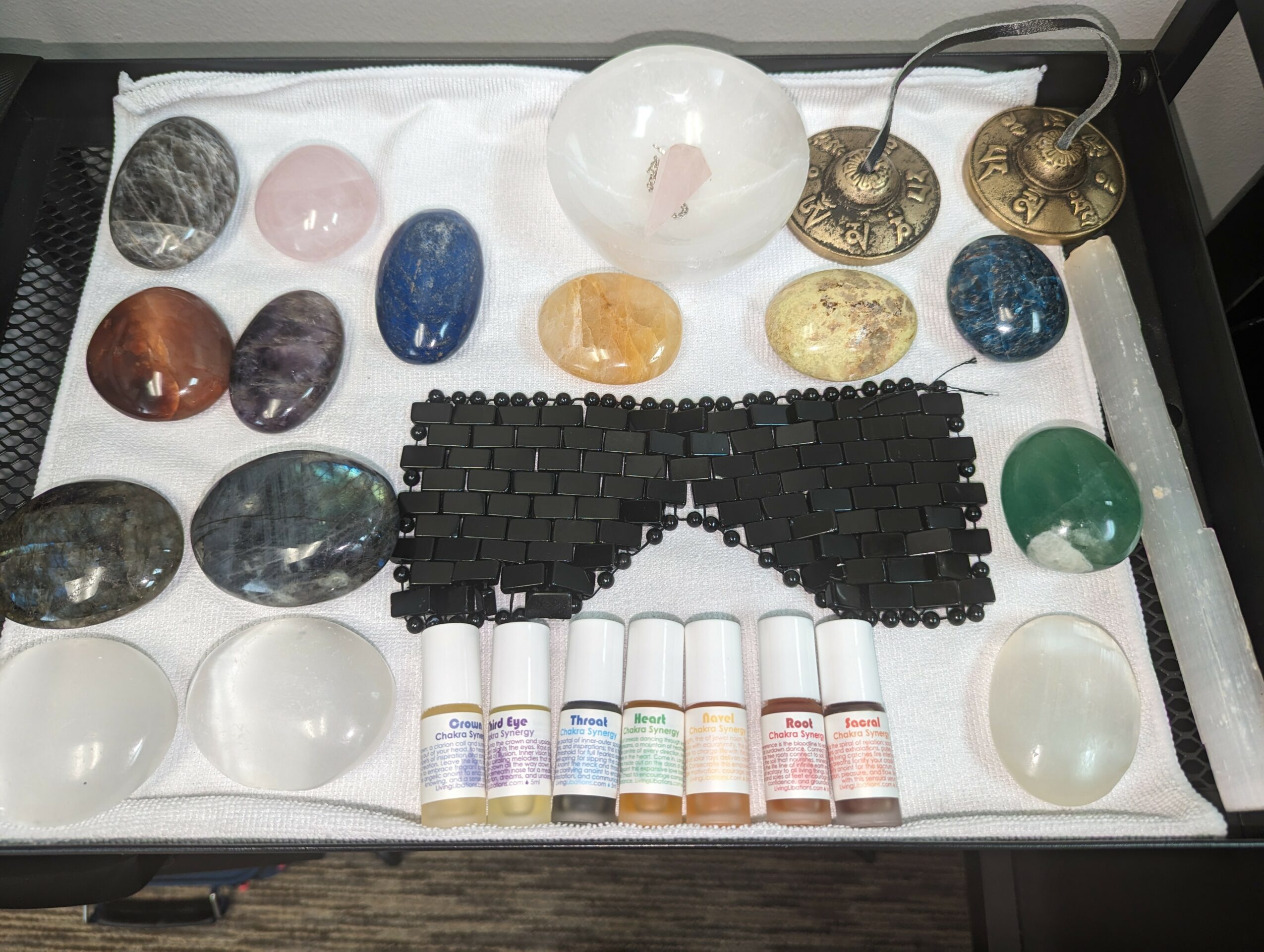 Collection of polished stones, a black keyboard, and small bottles of paint on a white cloth surface.