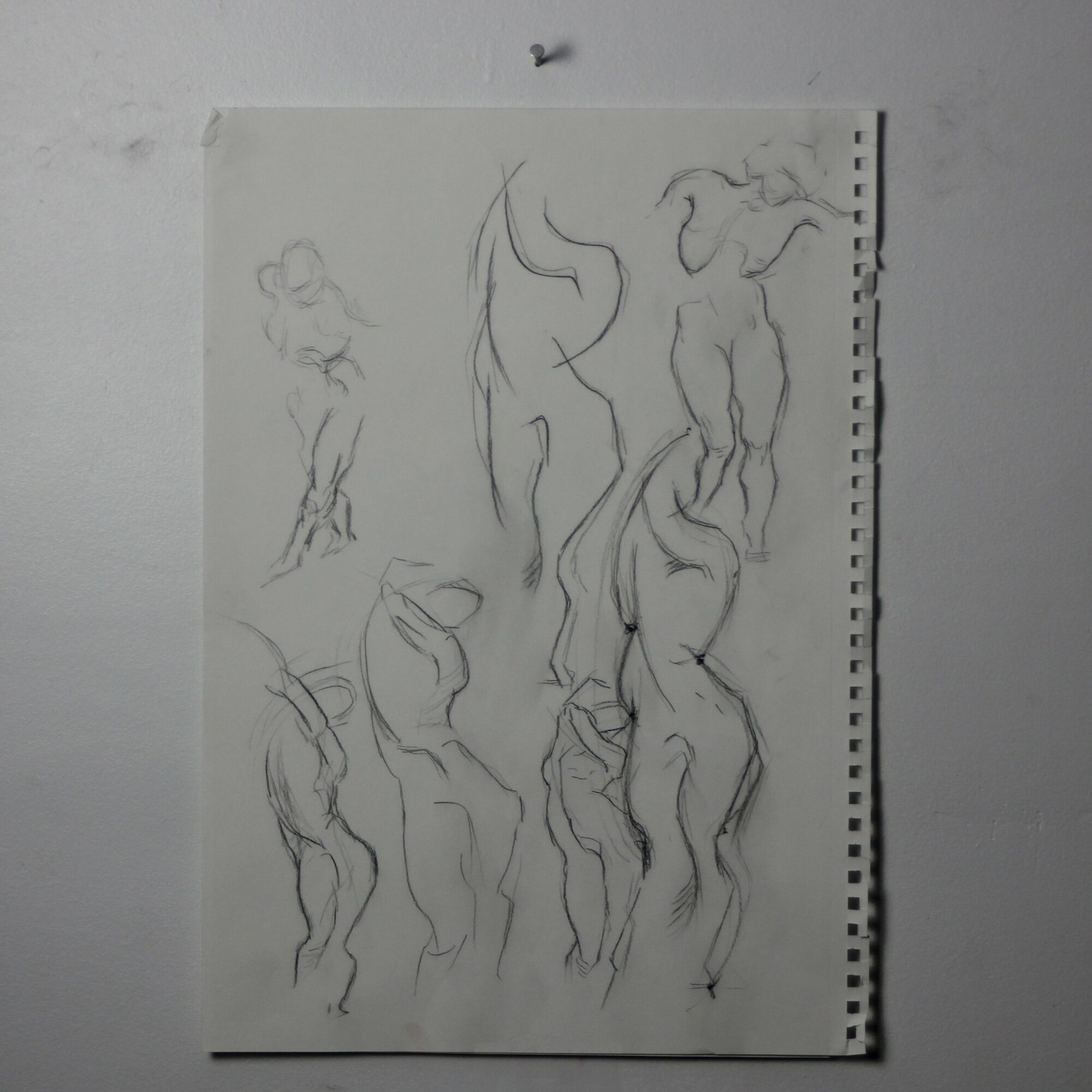 Sketches of multiple human figures in various poses on a piece of paper.