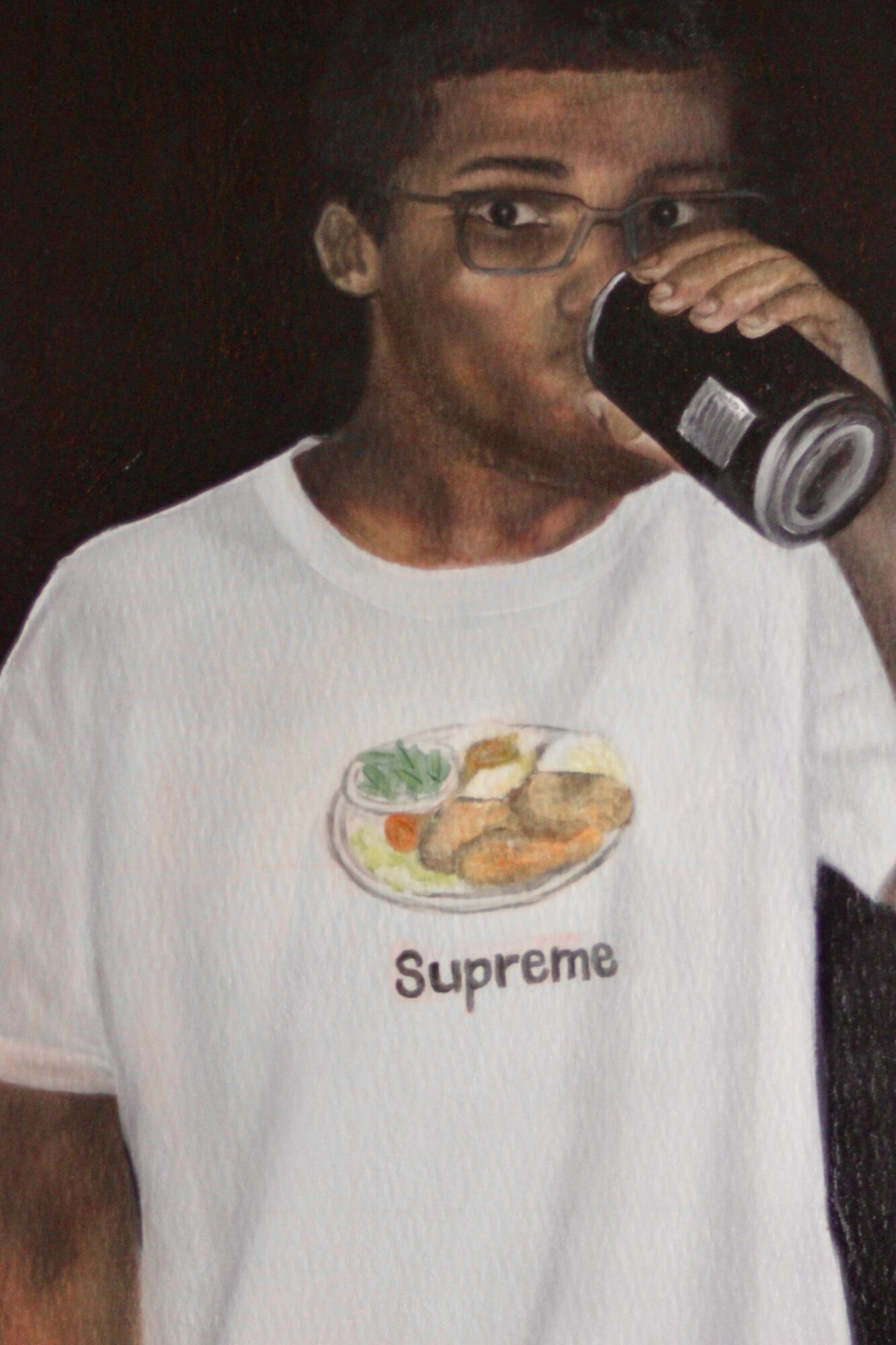 Person with glasses drinking from a can, wearing a white T-shirt with a food illustration and the word 'Supreme'.