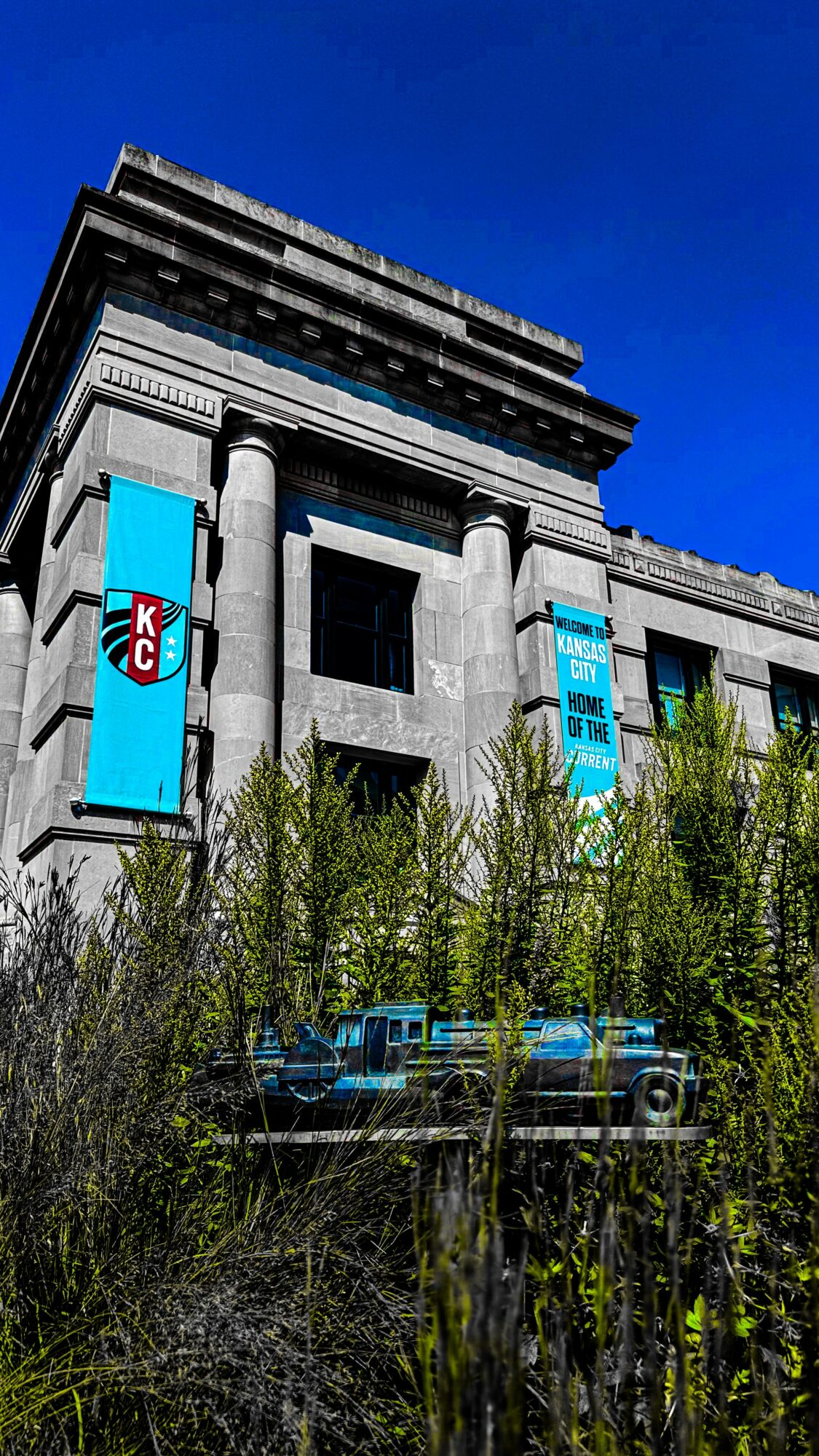 A large building with banners, trees in front, and a clear blue sky background.