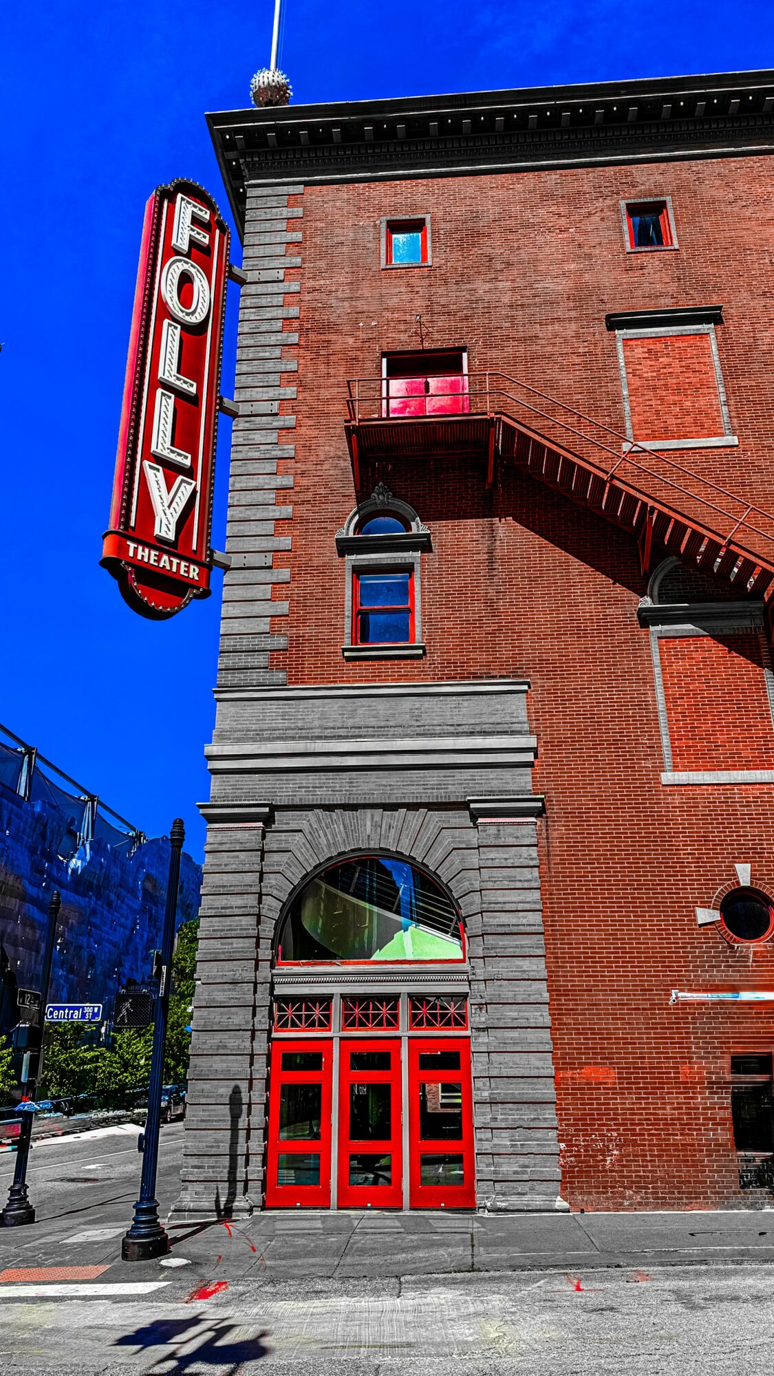 The building has a red brick facade with a theater sign reading 'HOLLY' vertically, and a red door at street level.