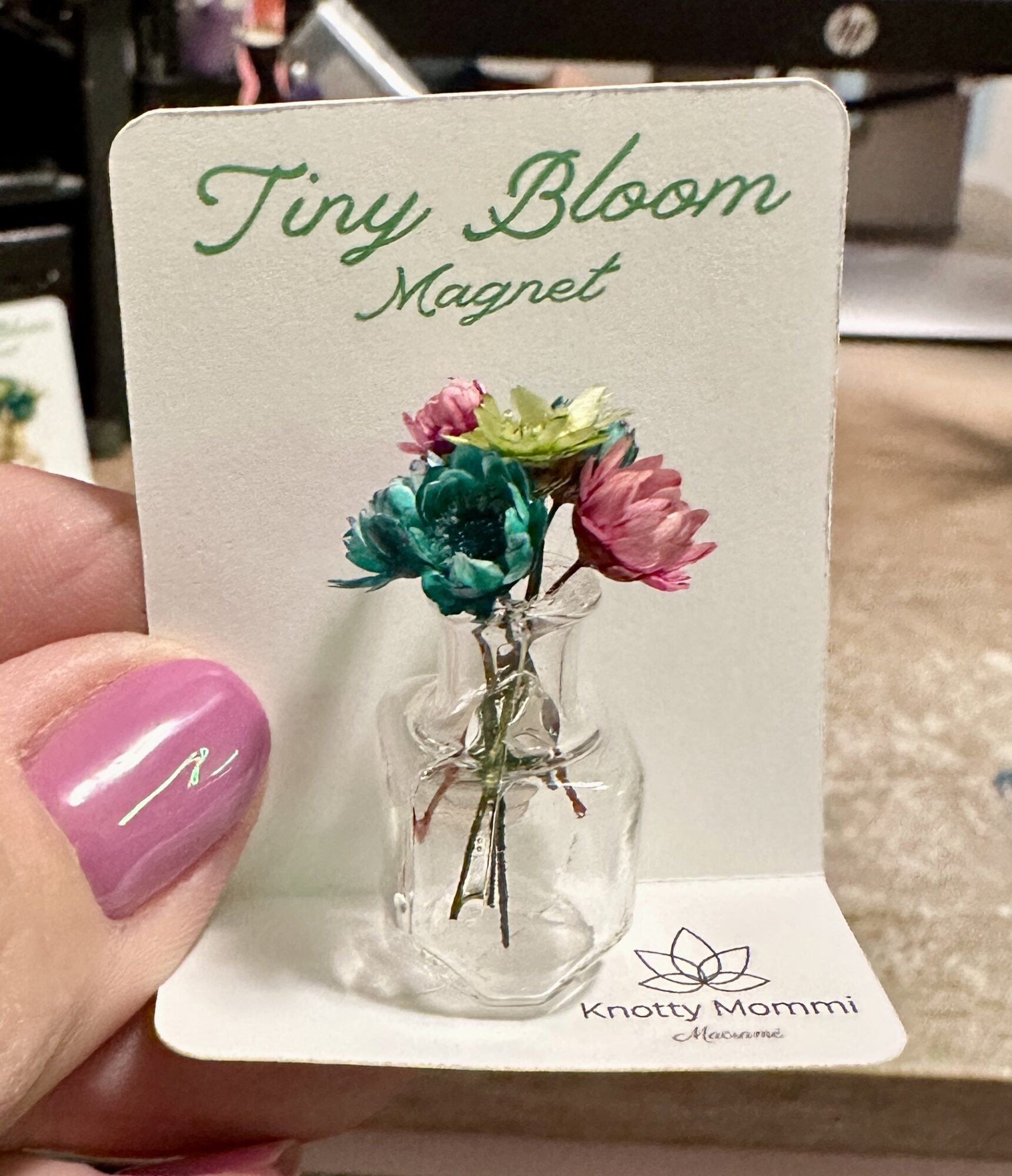 Small card with a glass vase holding colorful paper flowers, labeled 'Tiny Bloom Magnet' and 'Knotty Mommi'.
