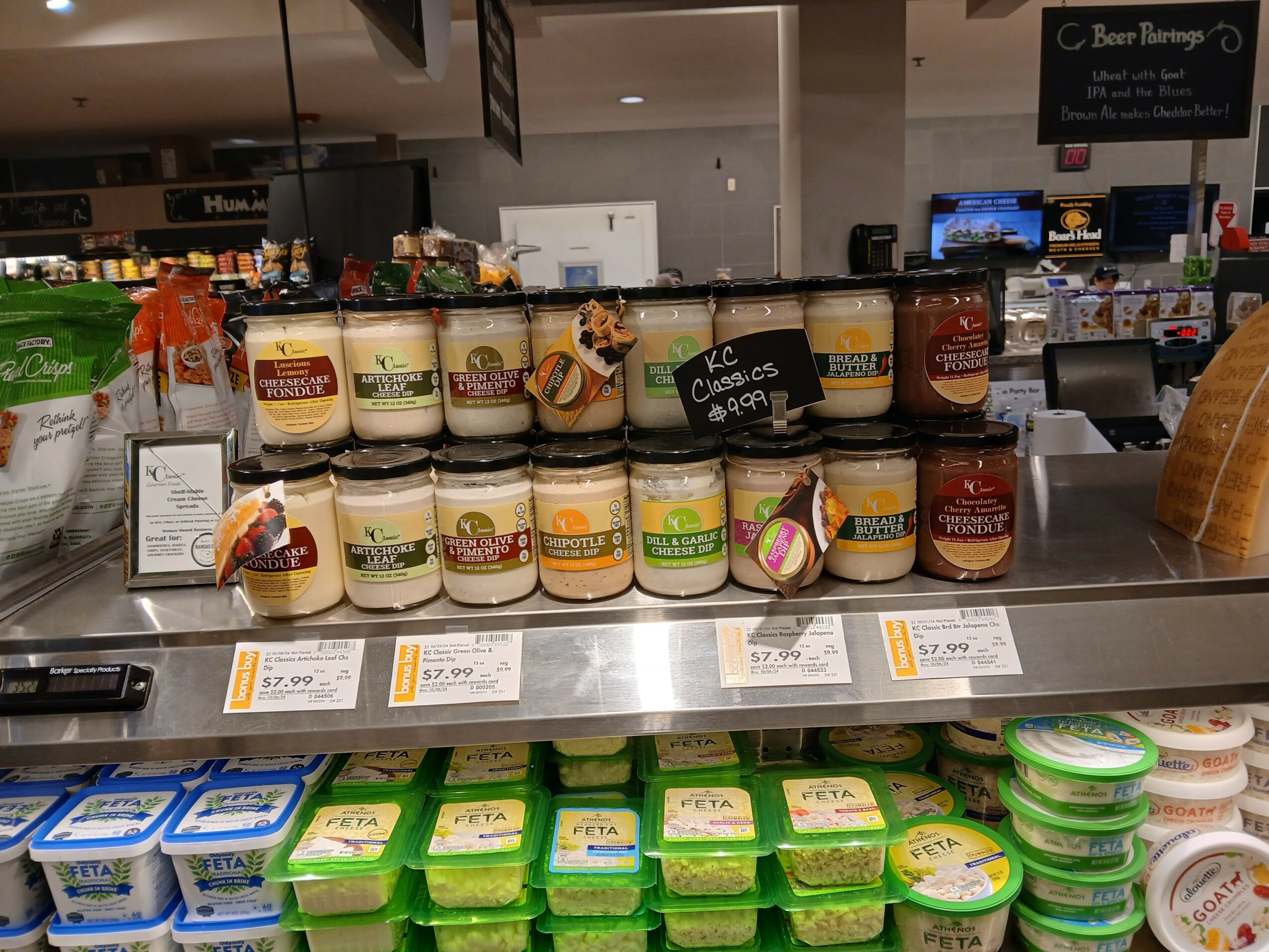 Display of various jars of spreads and containers of butter or margarine in a grocery store, with price tags below.