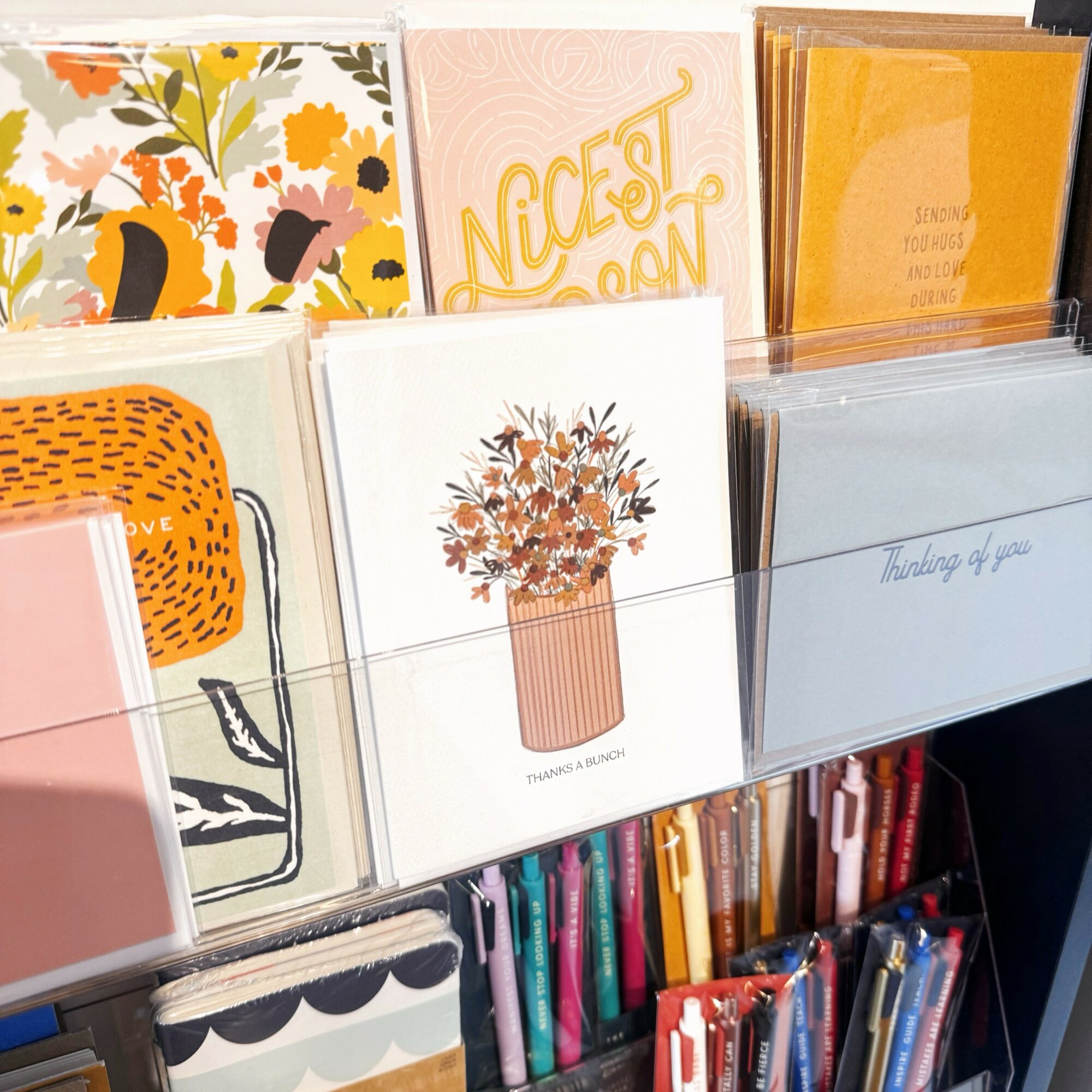 Display of greeting cards with floral, text, and abstract designs on a rack.