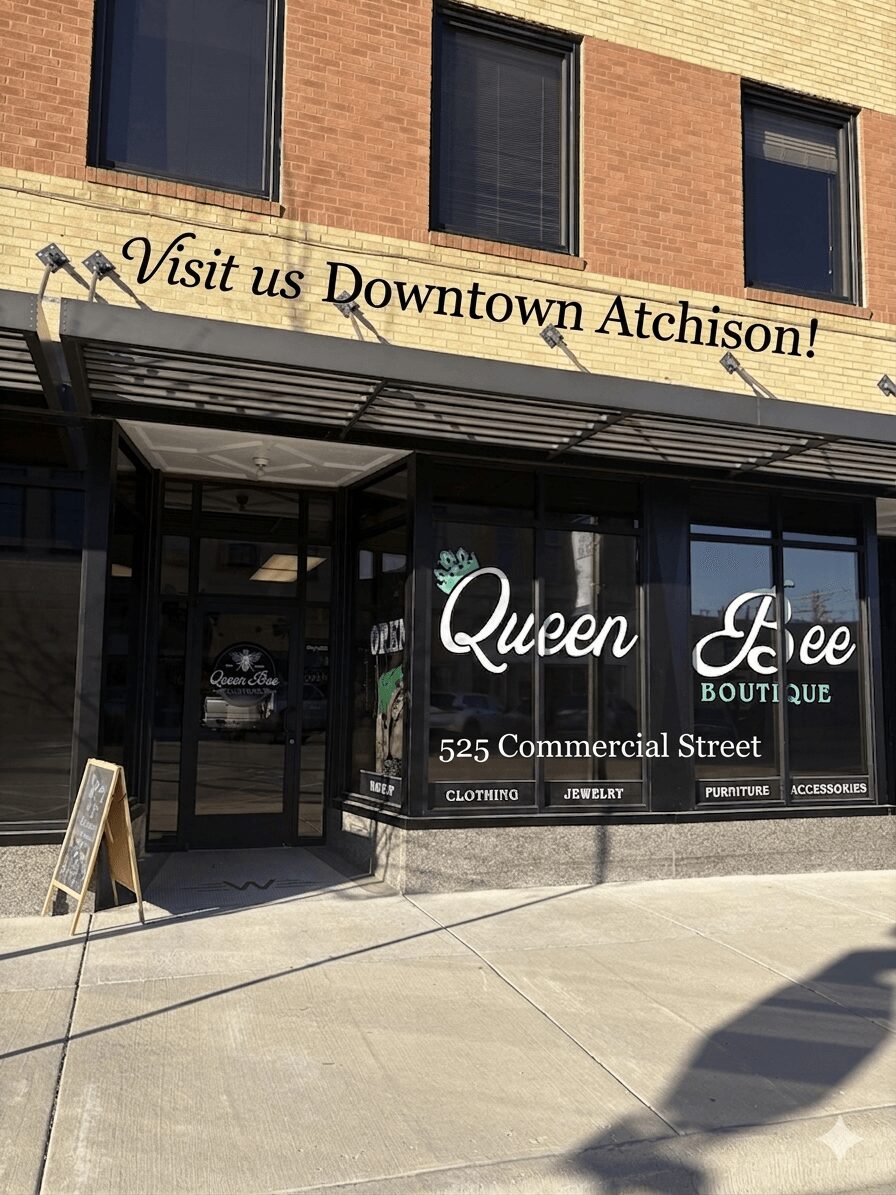 Storefront with signage for Queen Bee Boutique at 525 Commercial Street, with a banner above inviting visitors to Downtown Atchison.