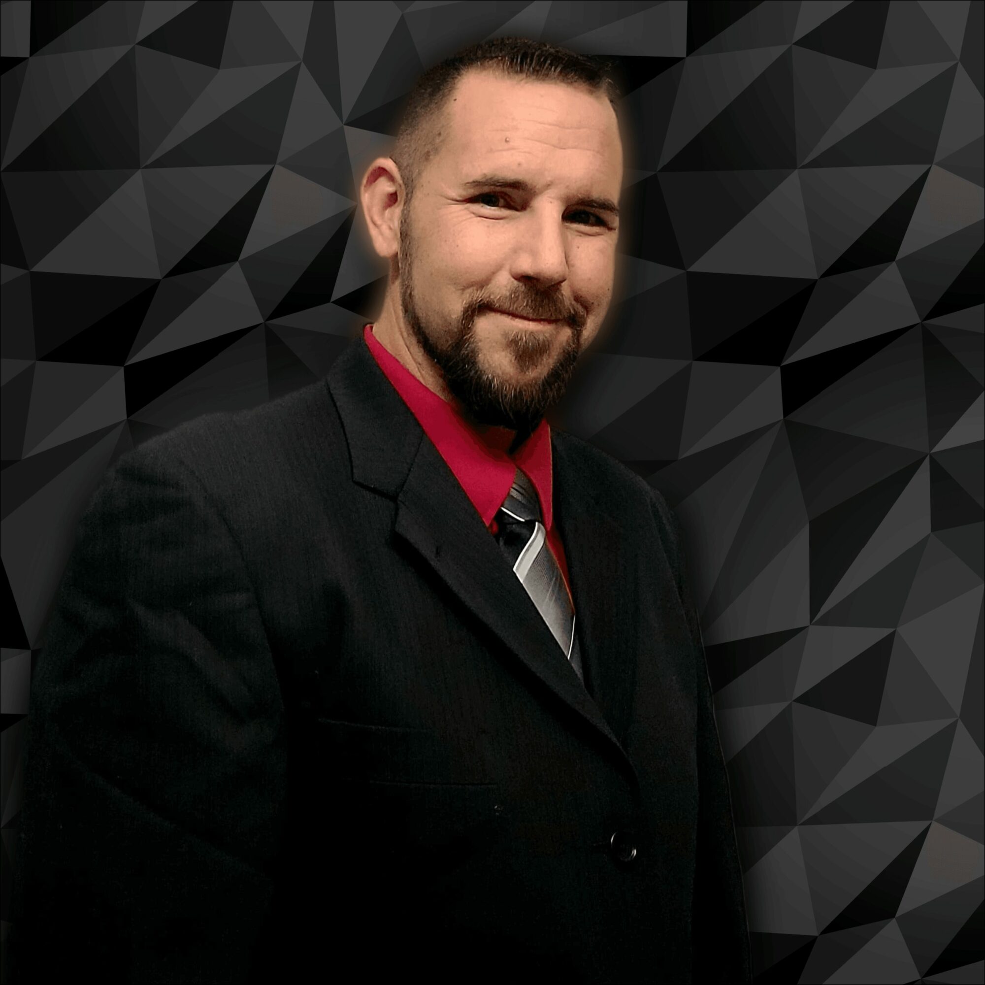 Man with short hair and beard in a suit, smiling, against a geometric black background.