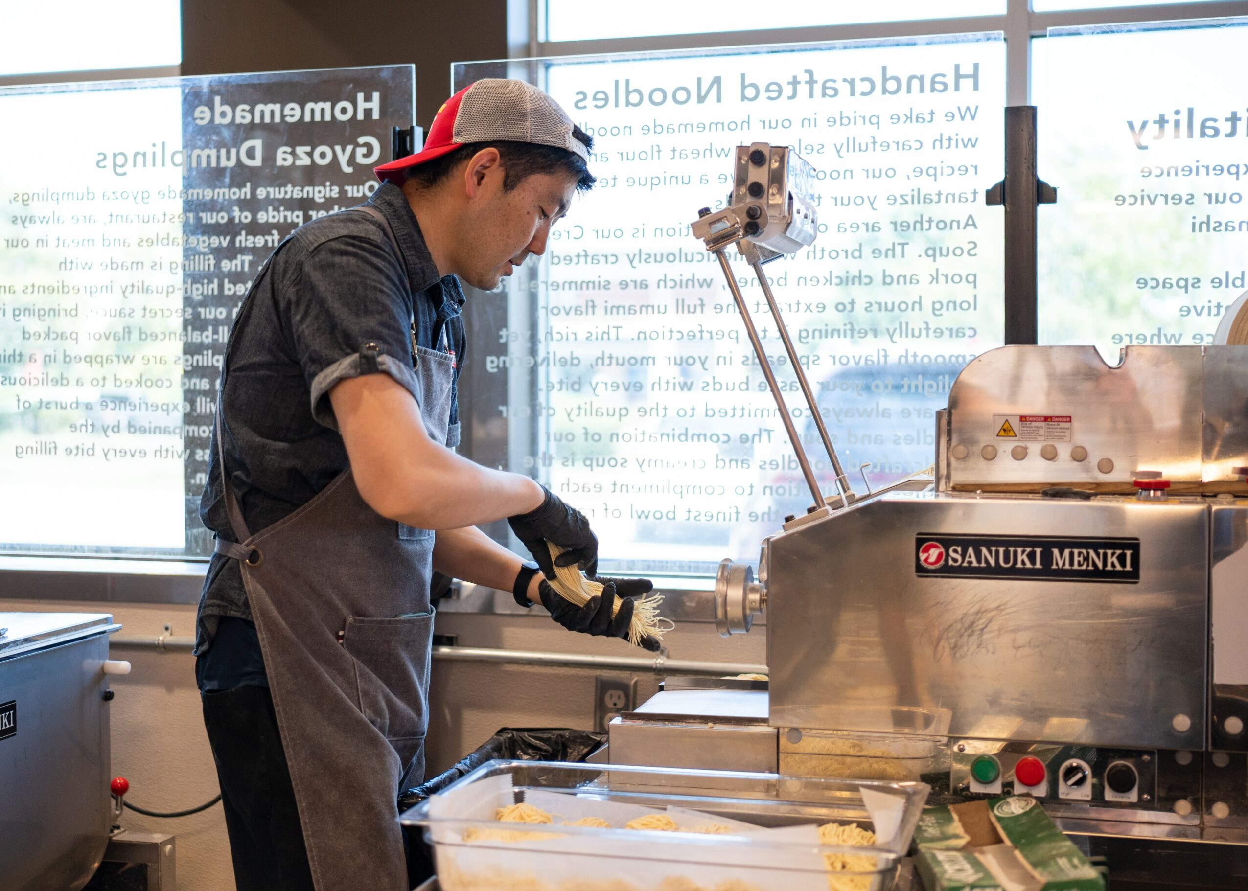 Person operating a food machine in a modern indoor setting with large windows and text on the glass.