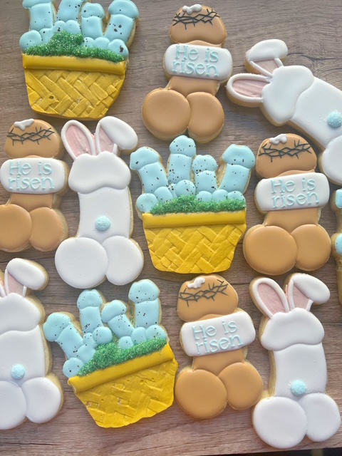 Assorted cookies with Easter-themed shapes, including bunnies, eggs, and cactus in baskets, on a wooden surface.