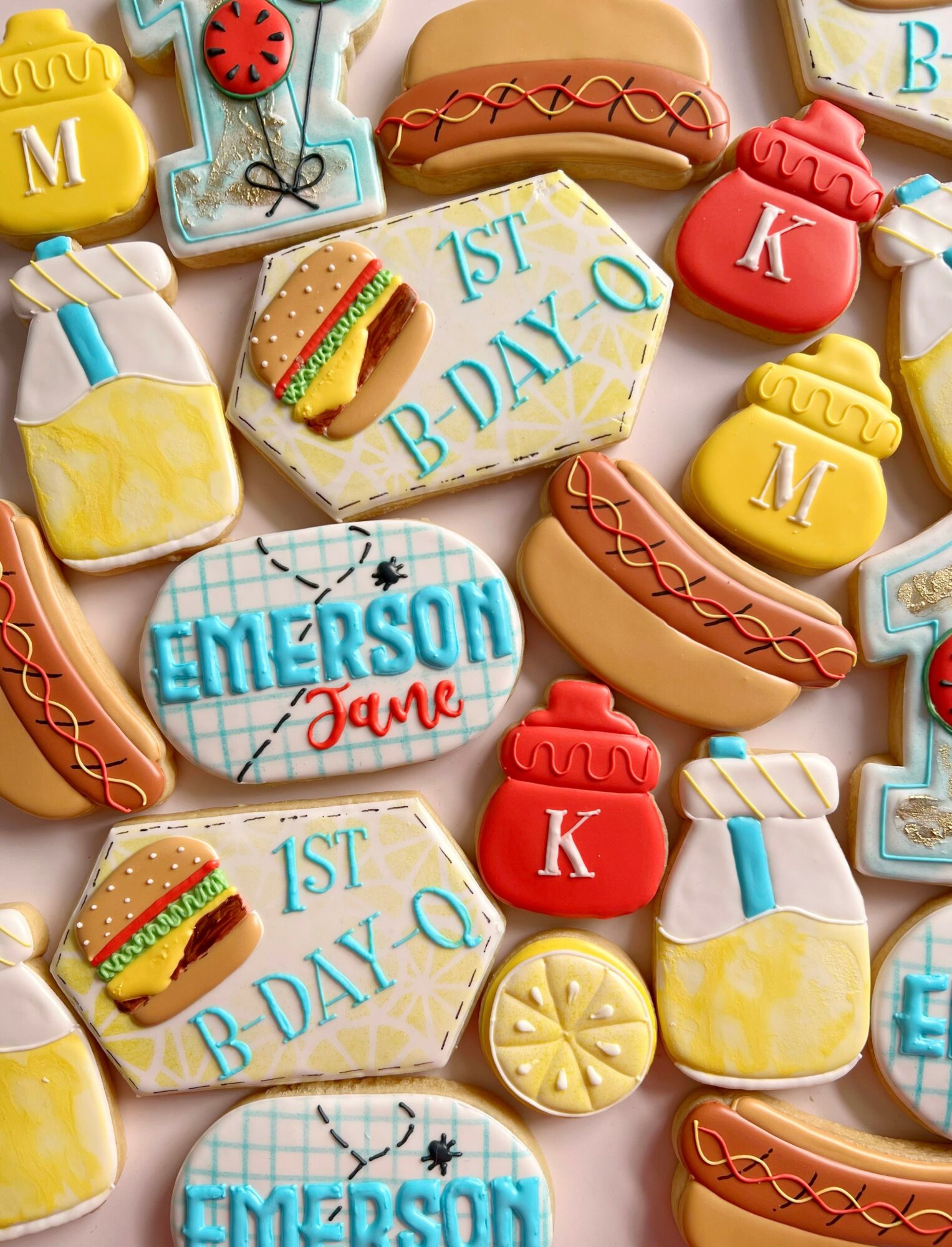 Cookies decorated with birthday themes, including hot dogs, ketchup bottles, and birthday messages, arranged on a surface.