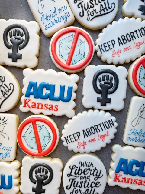 Cookies with messages about abortion rights, liberty, and justice, some with symbols and logos, arranged on a surface.