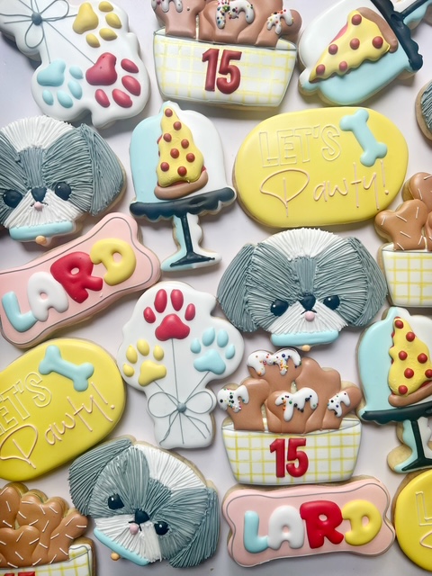 Collection of decorated cookies with dog, paw prints, bones, and birthday themes, including the number 15 and the name Lara.