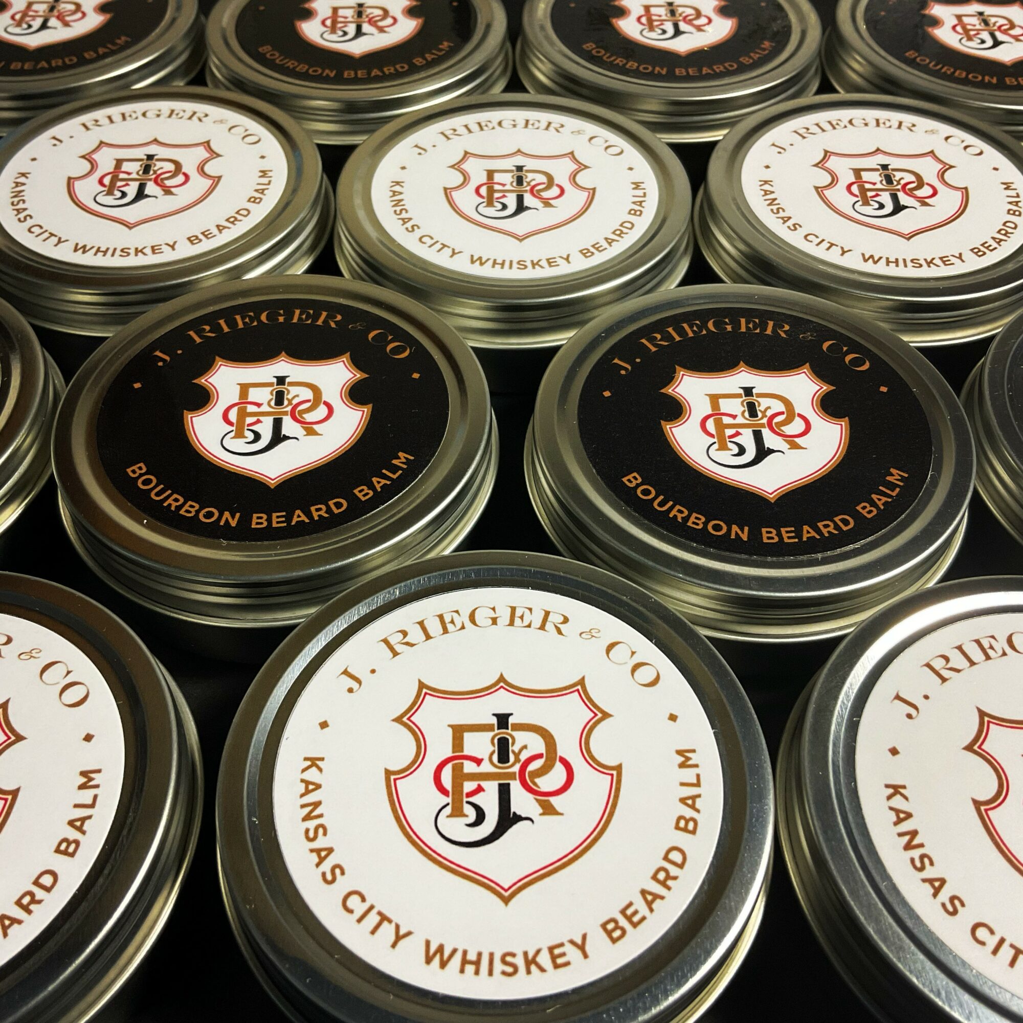 Close-up of round containers labeled Bourbon Beard Balm with a logo and text, arranged in a grid pattern.