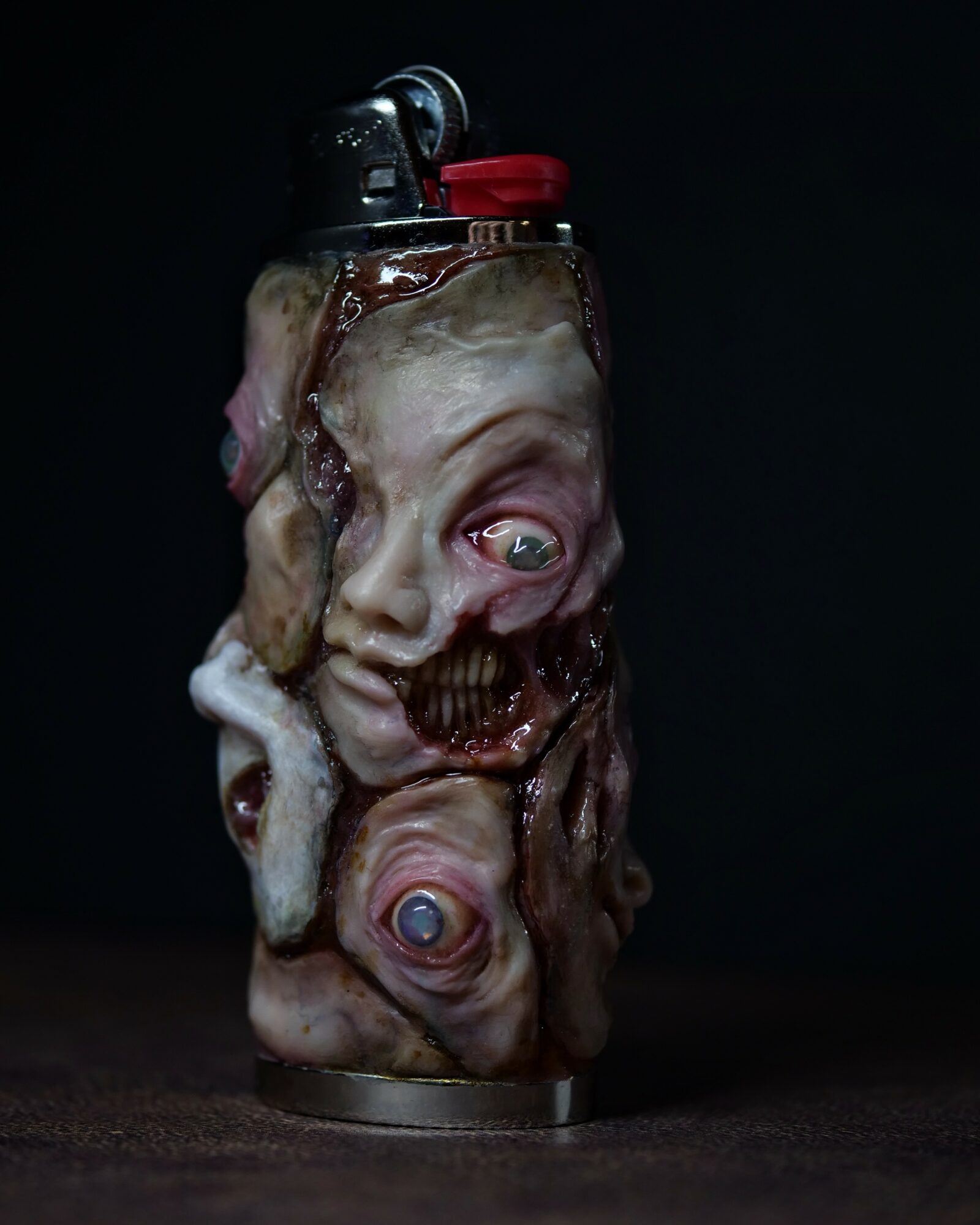 A can with a disturbing, melted, and distorted face with multiple eyes and a skull, against a dark background.