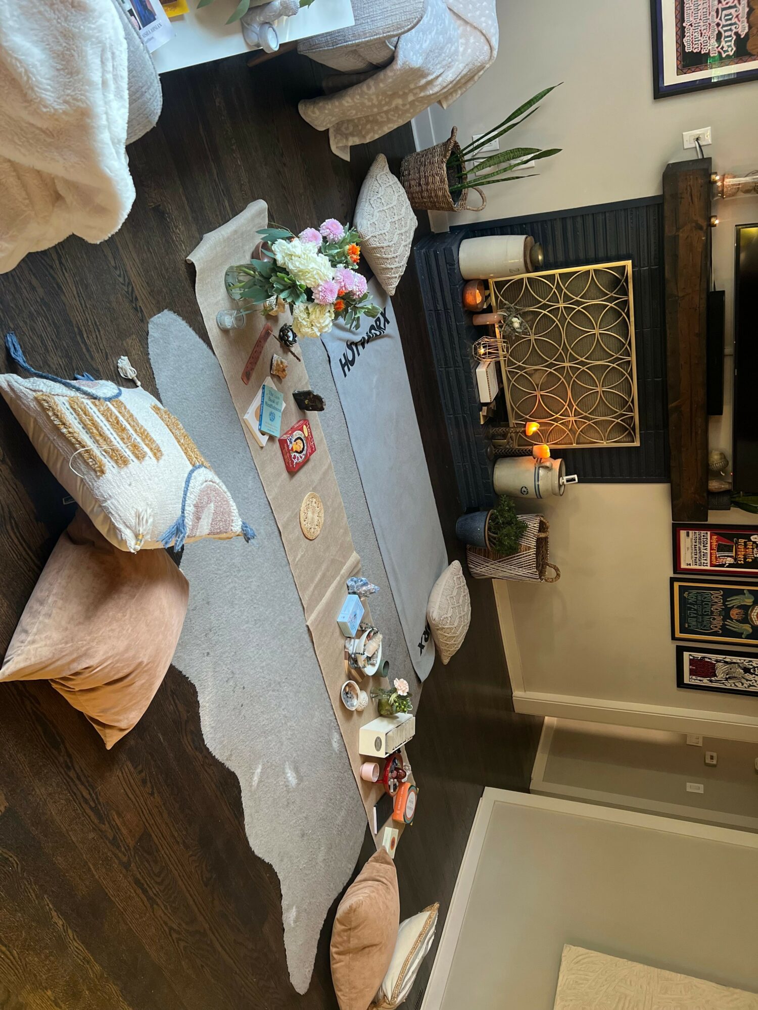 Living room with a low table, cushions, and a flower arrangement on the floor in front of a fireplace.
