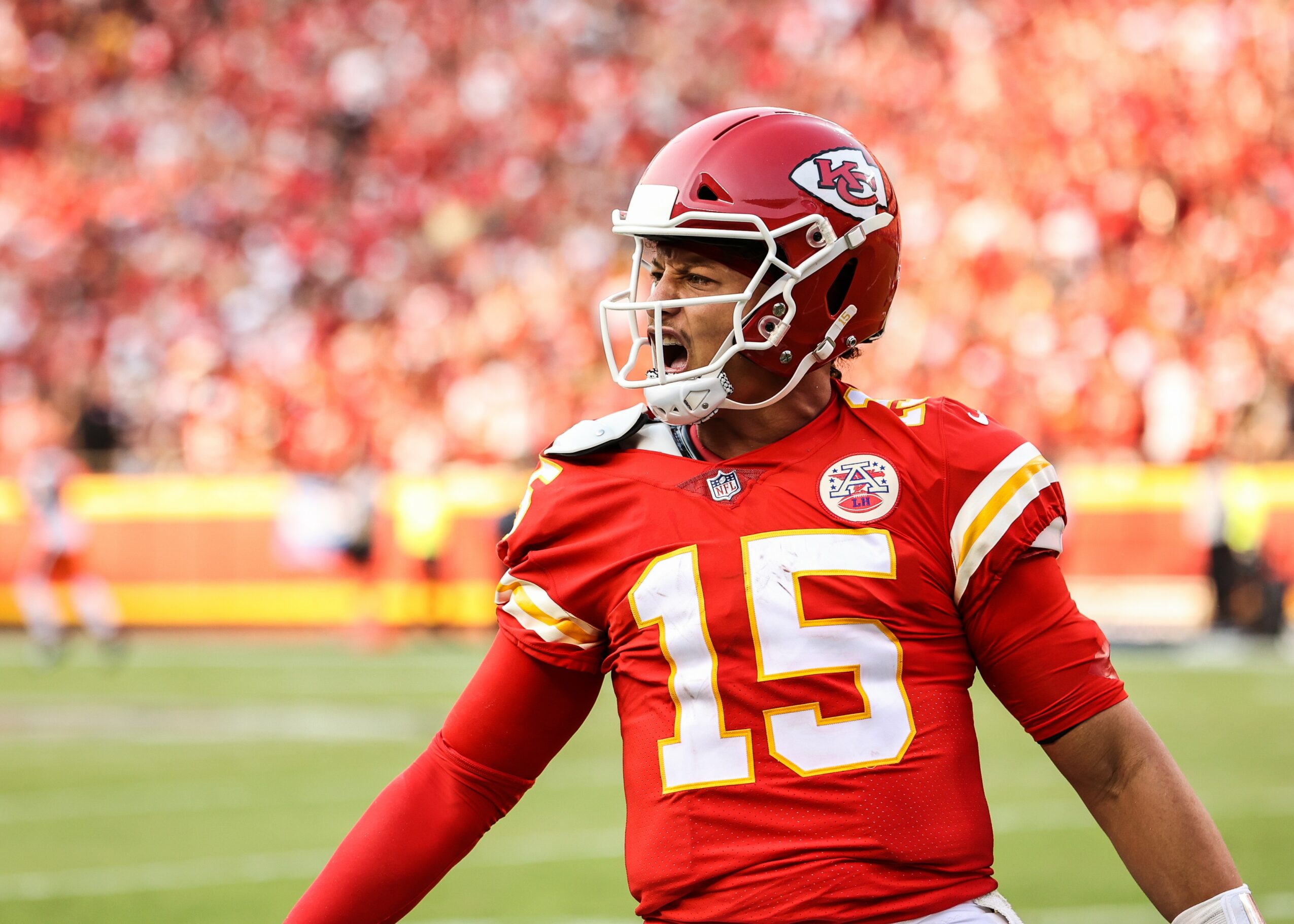 Football player in red uniform and helmet on field, crowd in background, celebrating or signaling.
