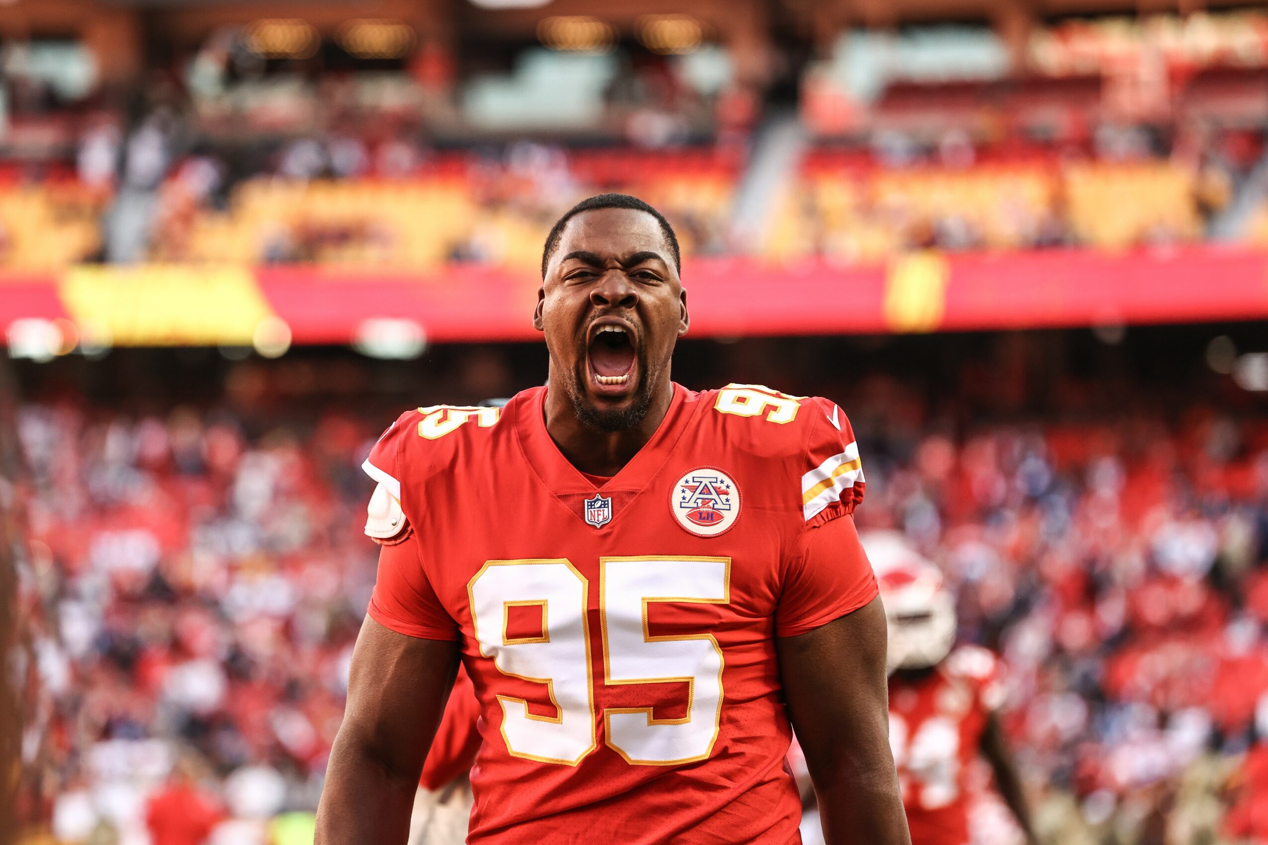 Football player in red uniform celebrating with mouth open in a stadium filled with spectators