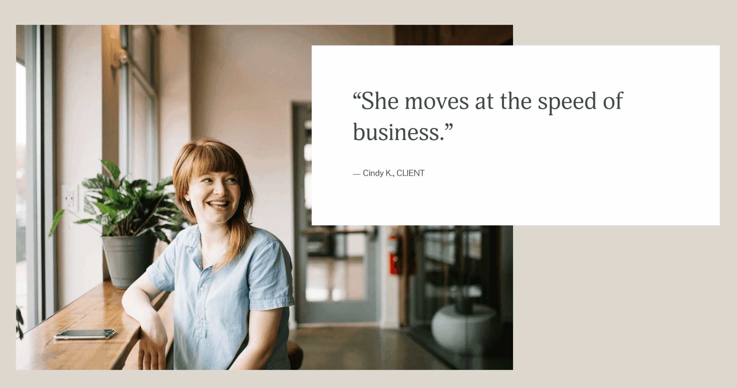 Smiling woman sitting at a desk in a bright office, with a quote about moving at business speed on a screen.