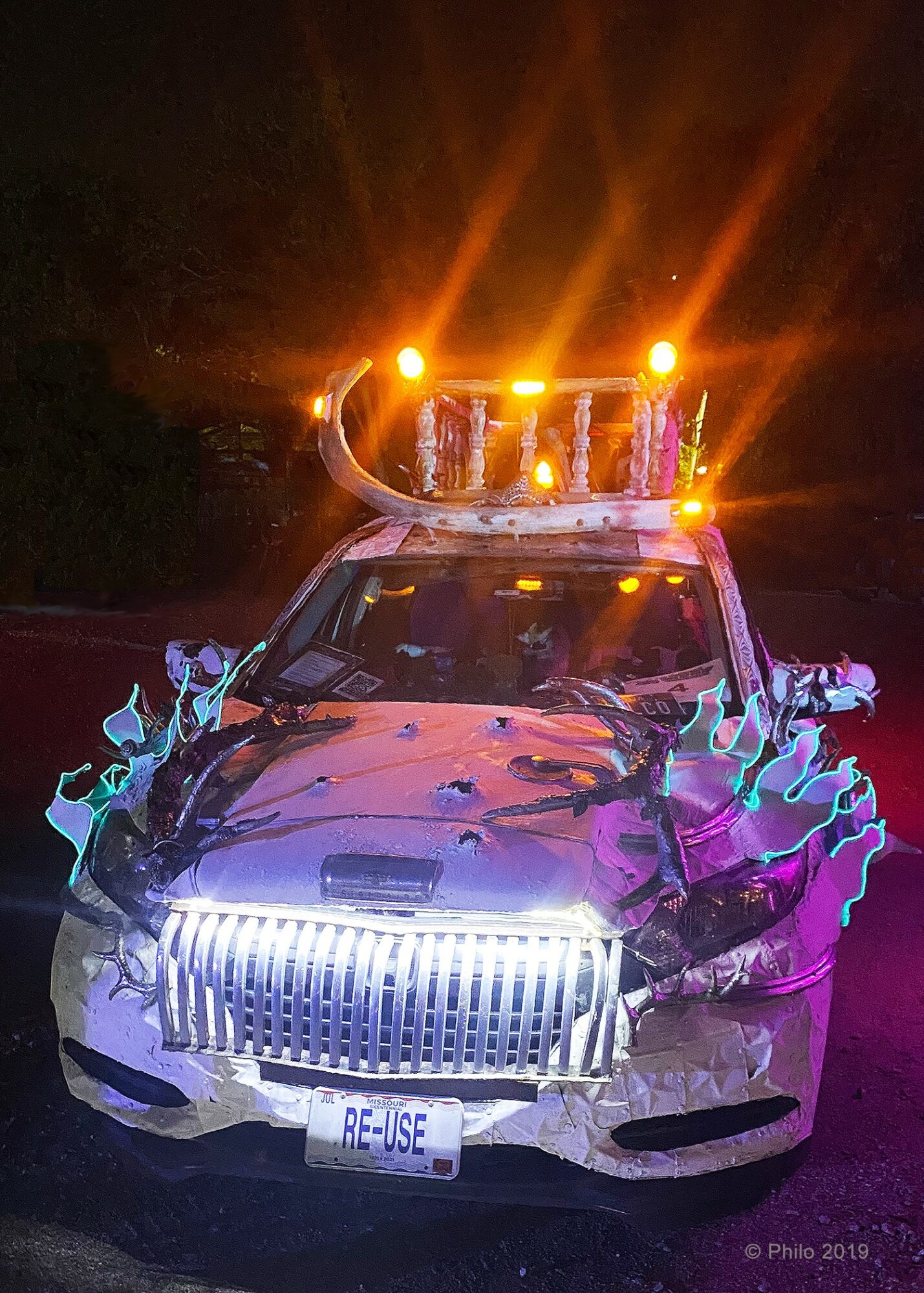 Damaged police car with flashing lights at night, water splashing from the front, and a damaged front grille.