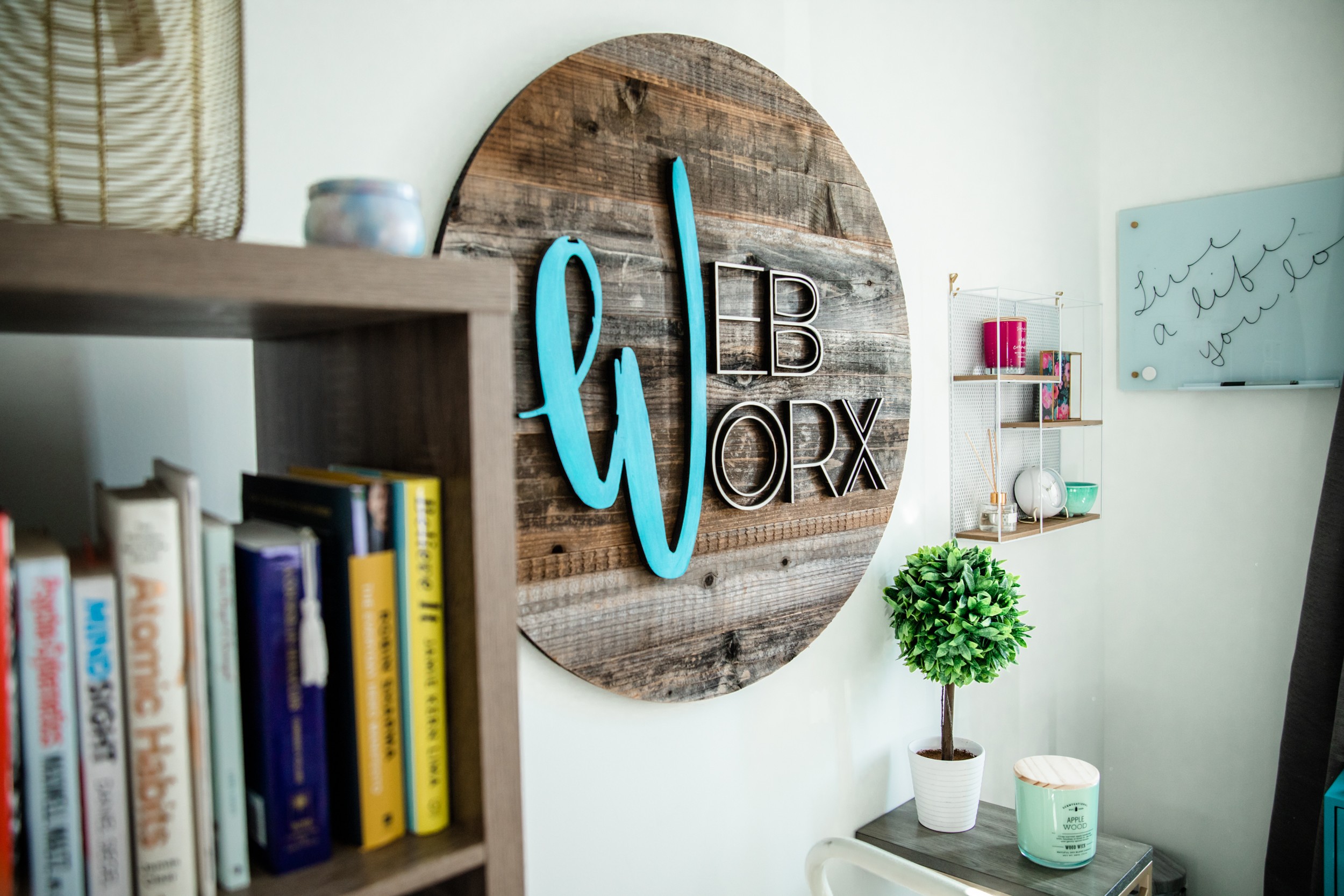 Decorative wall sign with a large blue letter 'W' and the word 'WORK' on a round wooden background, in a room.