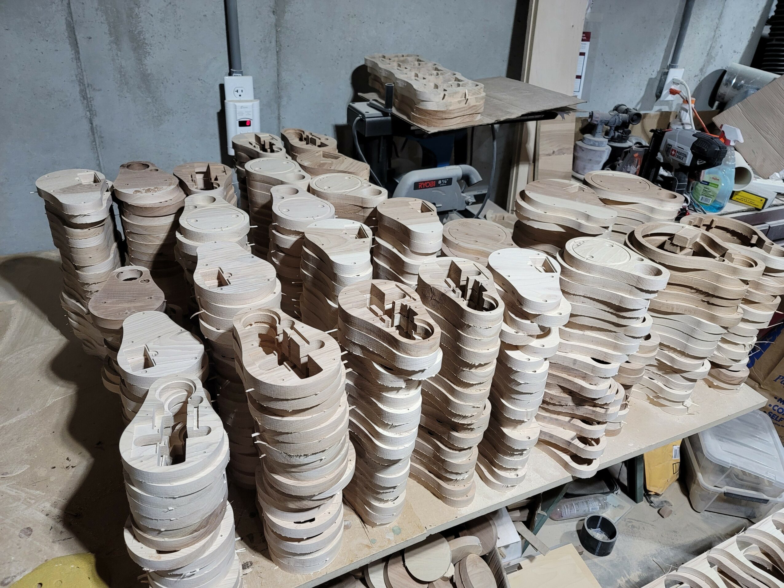 Wooden objects stacked on a table in a workshop, with tools and materials in the background.