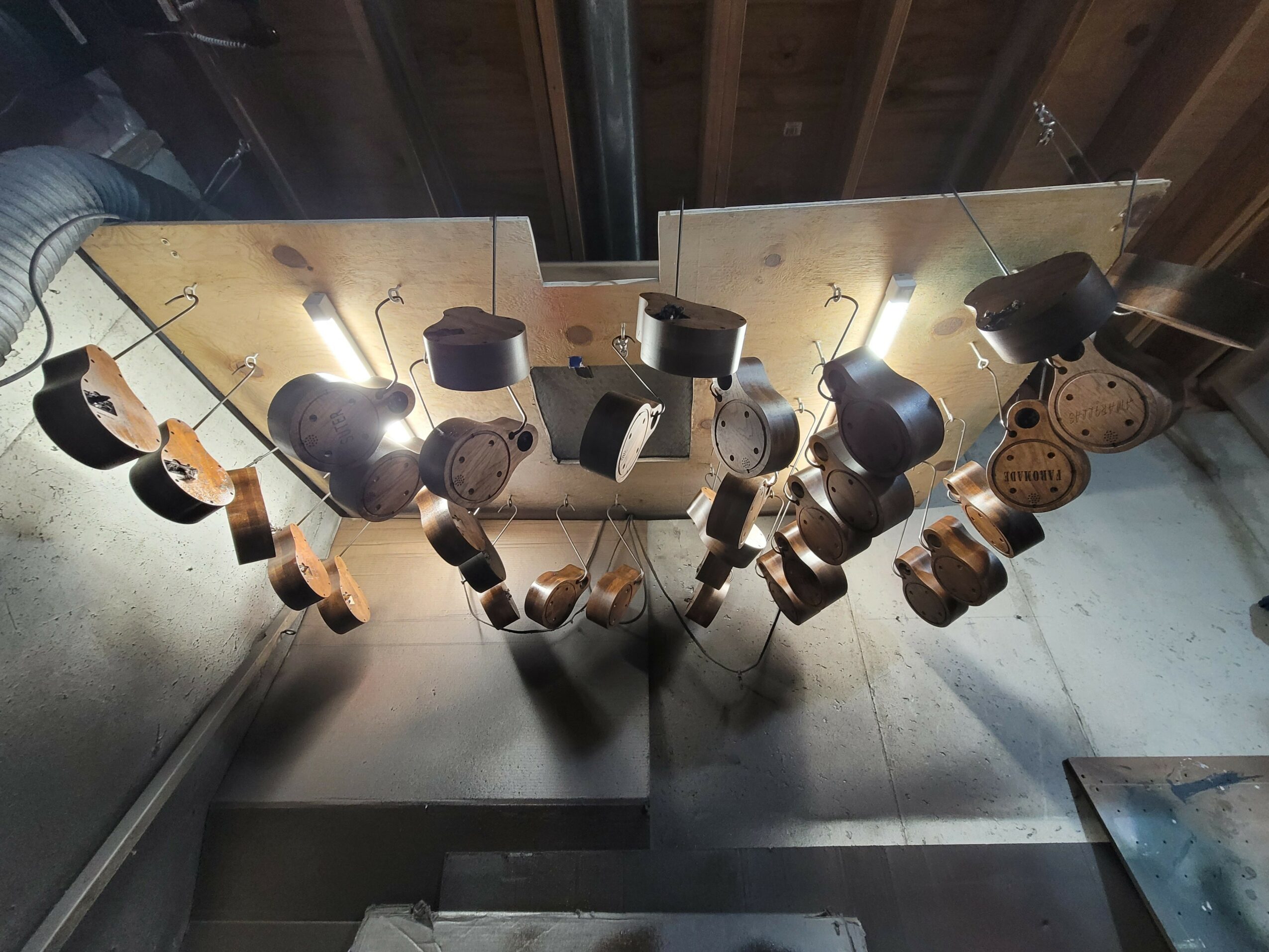 Reflection of a glass table with various black and brown objects, including cups and containers, on a wooden ceiling and floor.