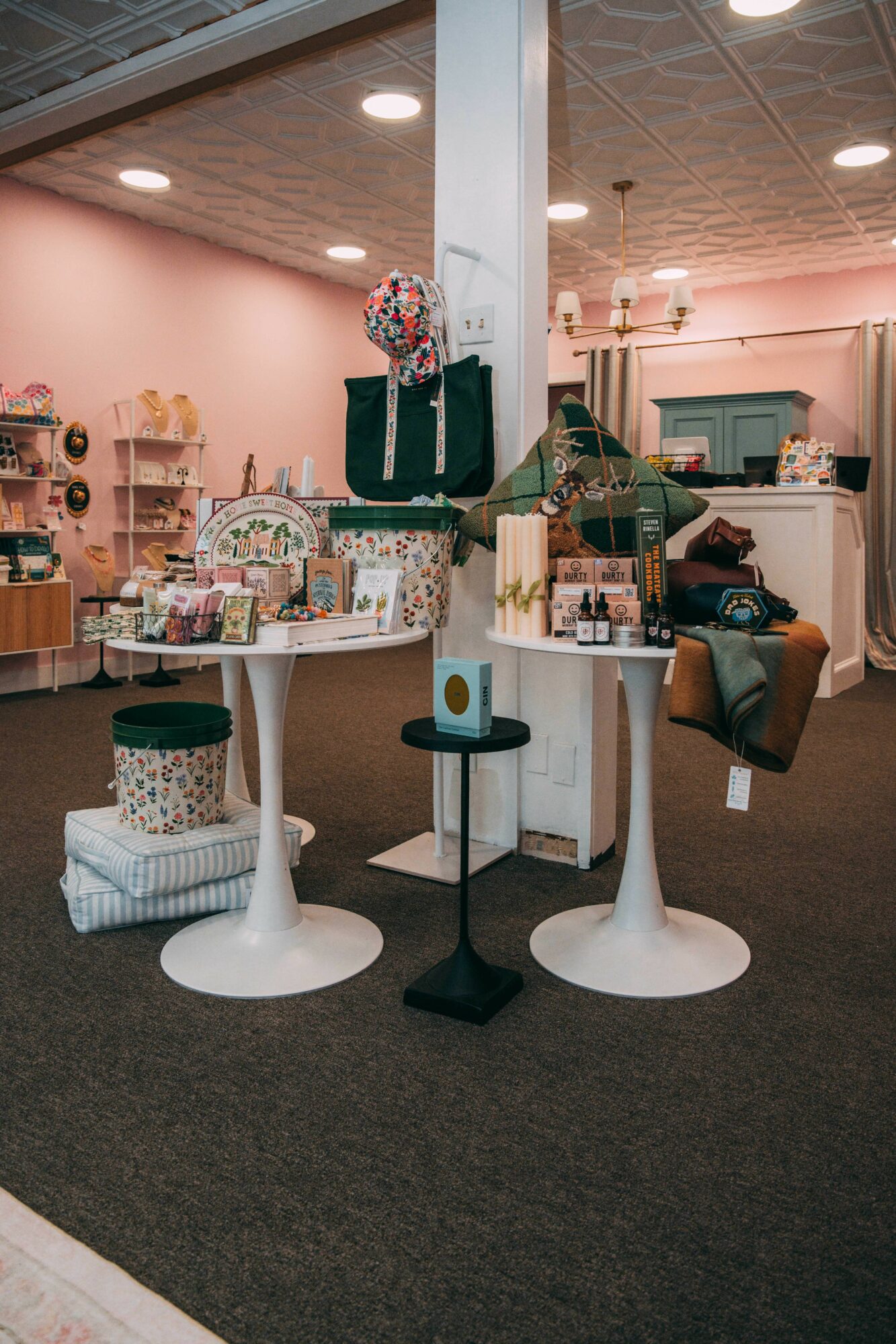 Interior of a store with display tables, shelves, and various products, including bags and decorative items.