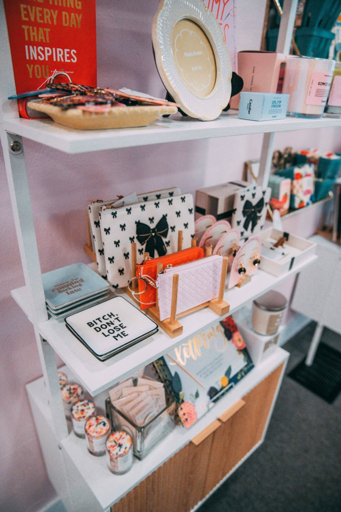 Shelves with decorative boxes, candles, and stationery items in a pink and white display area.