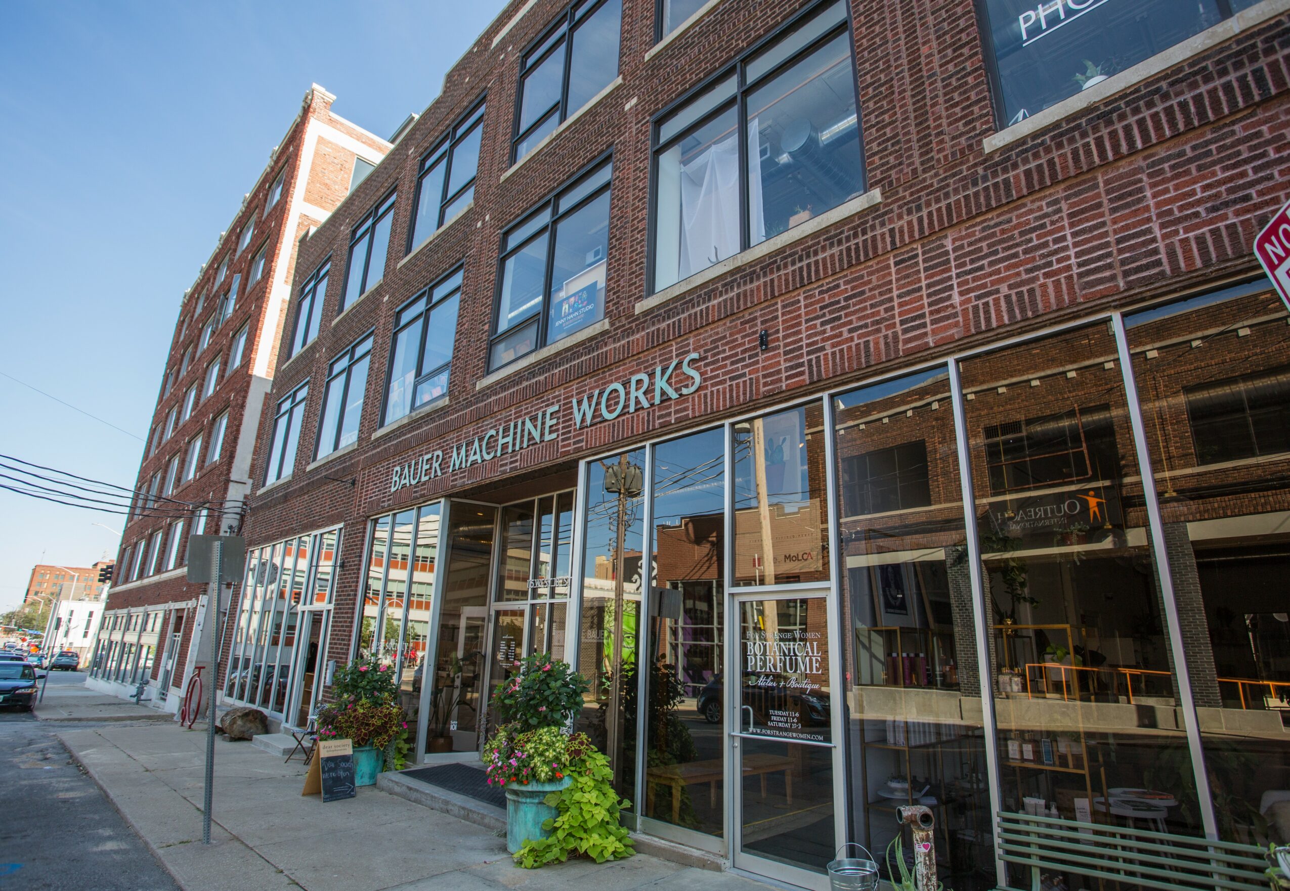 Street view of a brick building with large glass windows and a sign reading 'BUBER MACHINE WORKS' on the facade.