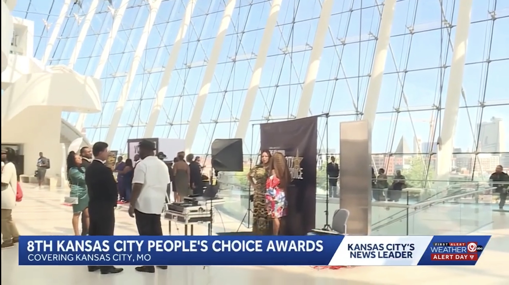 People attending the 8th Kansas City People's Choice Awards in a large, modern venue with a glass ceiling and natural light.