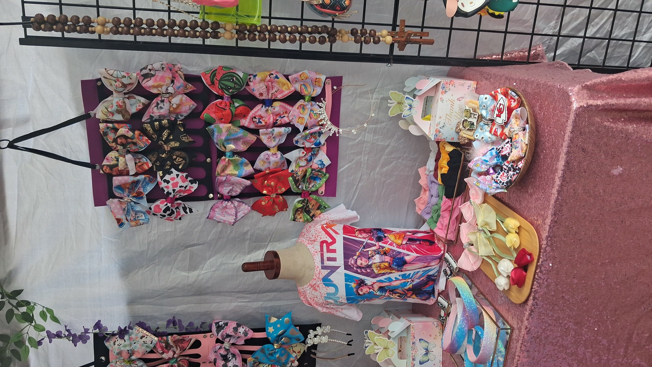 Display of colorful kimonos, a cake, and decorative items on a table, with a pink tablecloth and a gray wall background.
