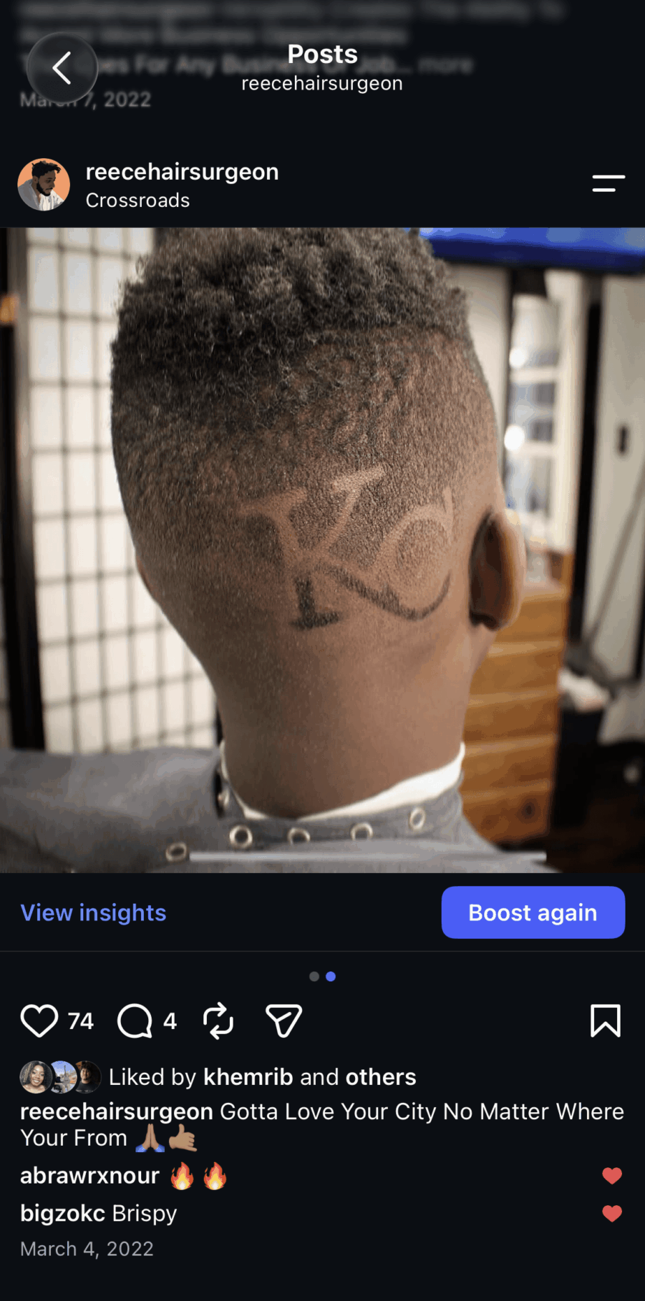 Back of a person's head with a tattoo of the letter 'K' and a small design, in a barbershop.