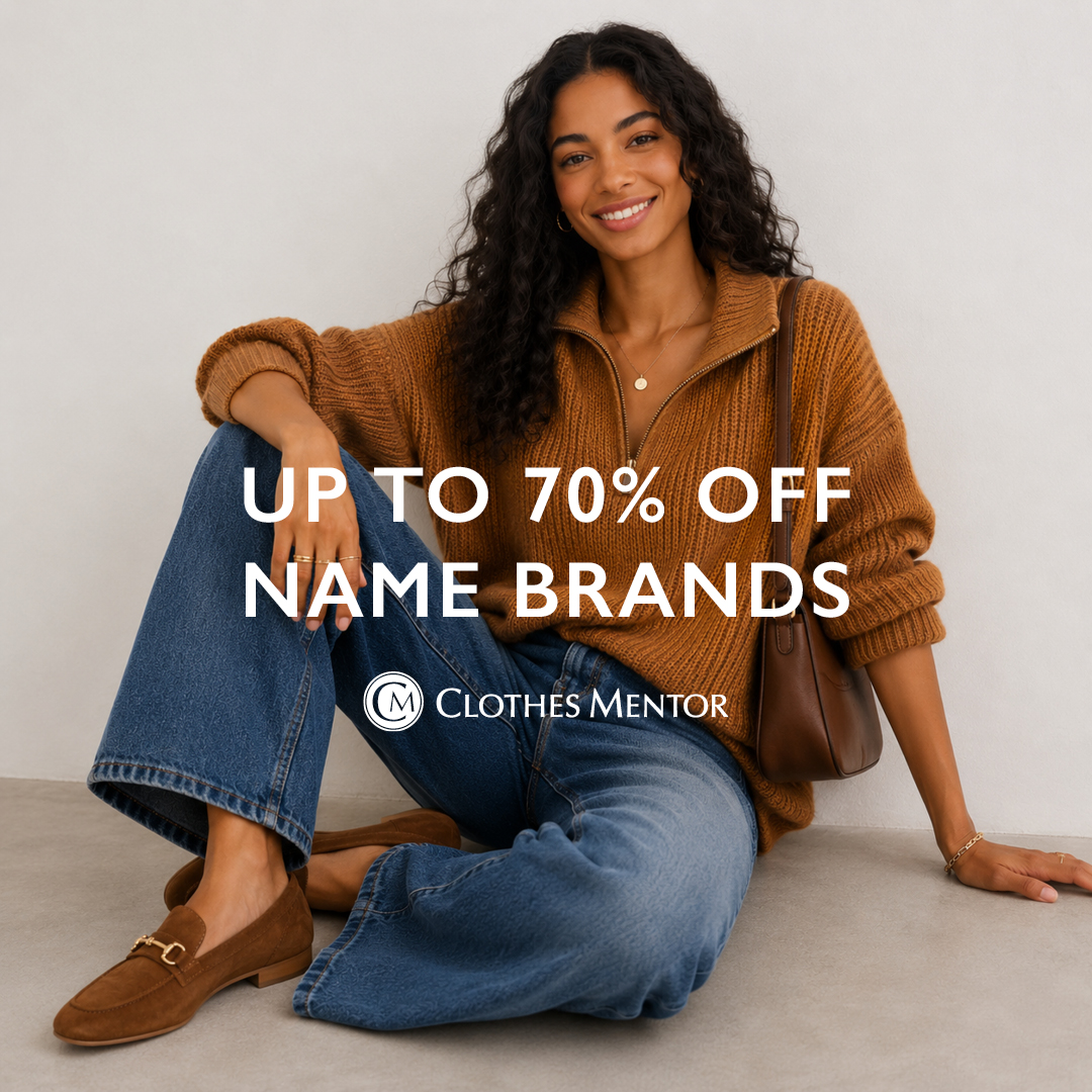 Smiling woman sitting on floor, wearing a brown sweater and blue jeans, promoting discounts on name brands.
