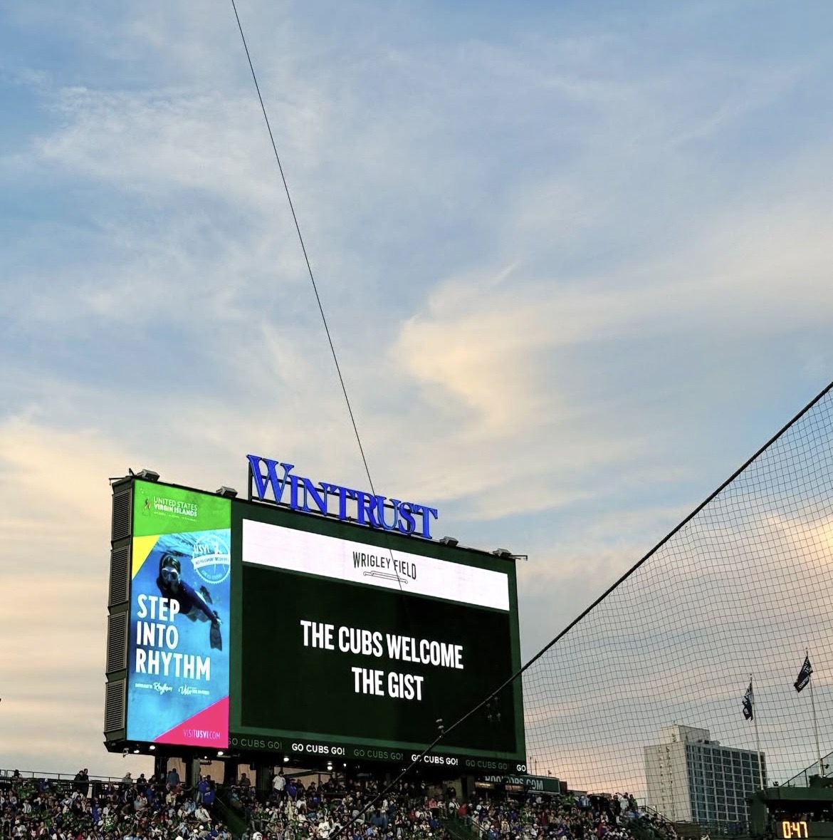 Large digital billboard displays a message welcoming the Cubs, with a blue sky and clouds in the background.
