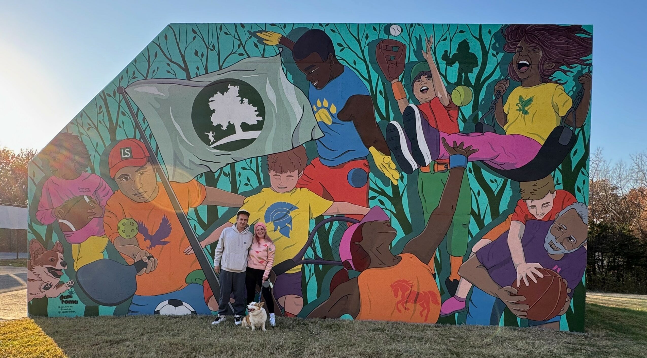 Colorful mural depicting diverse children playing sports and engaging in outdoor activities, with trees and nature in the background.