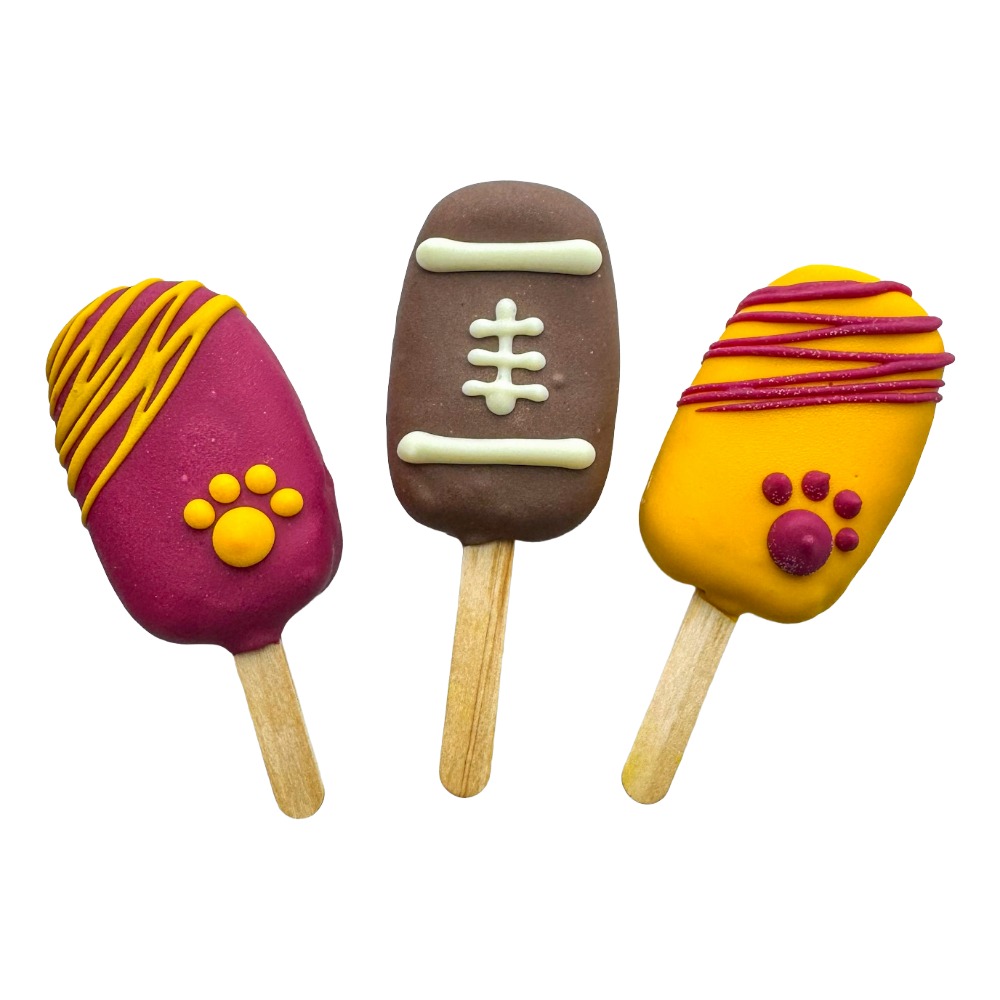Three decorated cookies on sticks: two with pink and yellow icing, one with brown and white icing resembling a football.