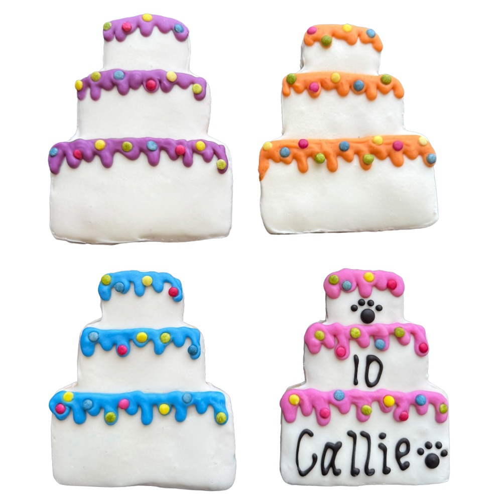 Four decorated cakes with colorful icing and candies, two with writing, on a white background.