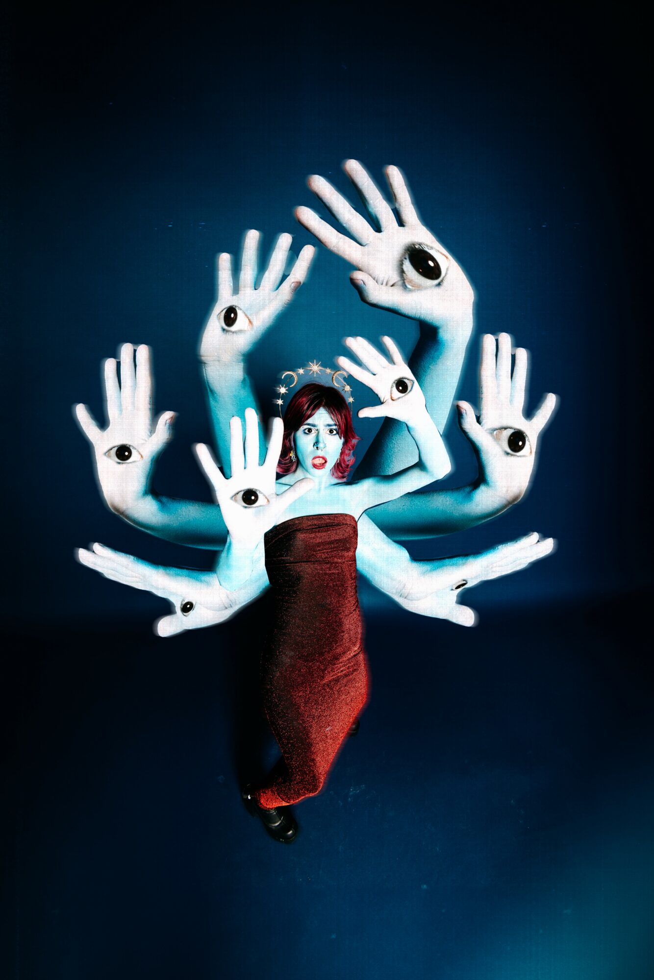 Person with multiple floating hands with eyes, wearing a red dress, against a dark background.