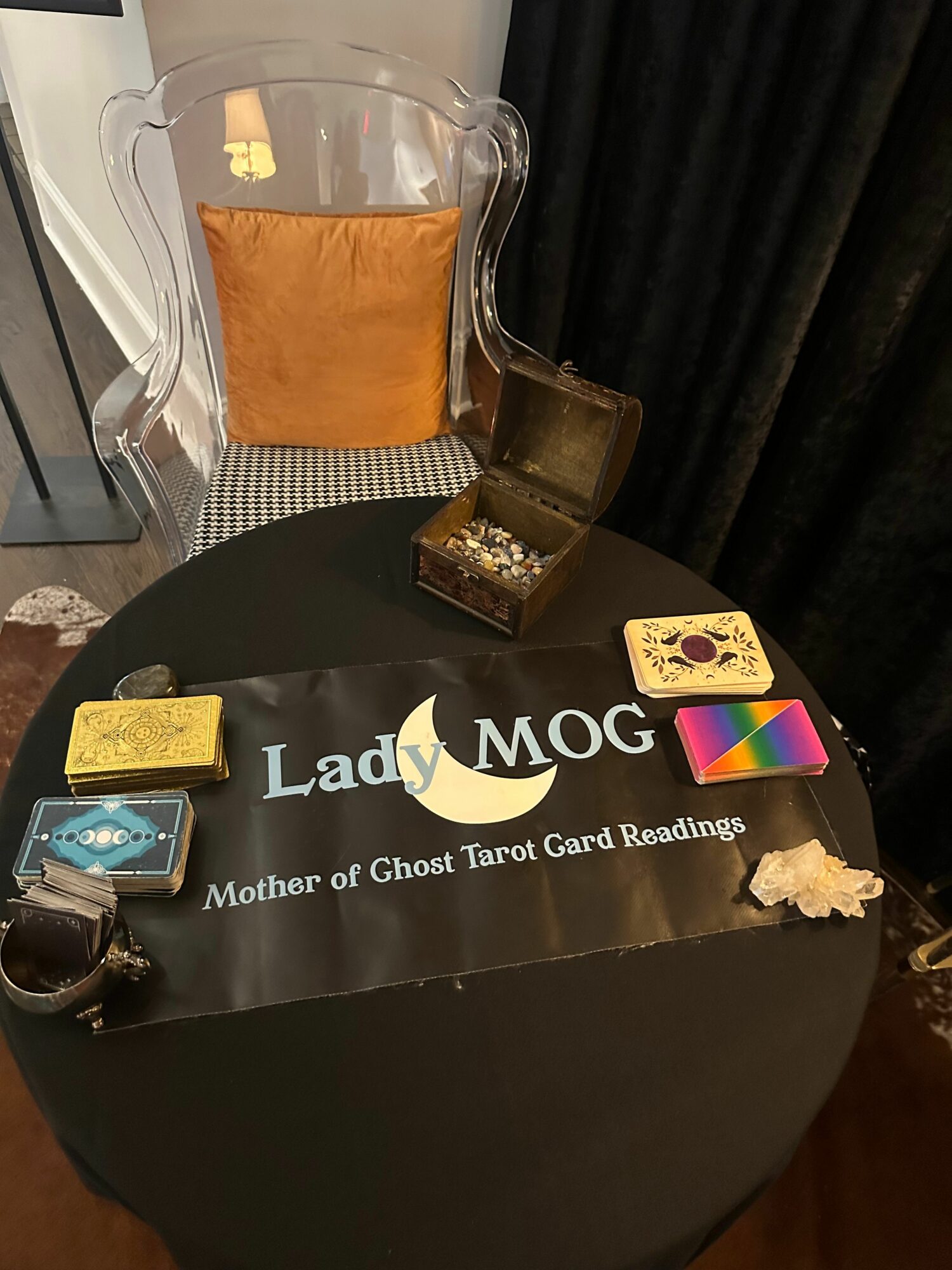 Round table with Lady Gaga memorabilia, a glass of whiskey, and a small white flower, against a dark background.