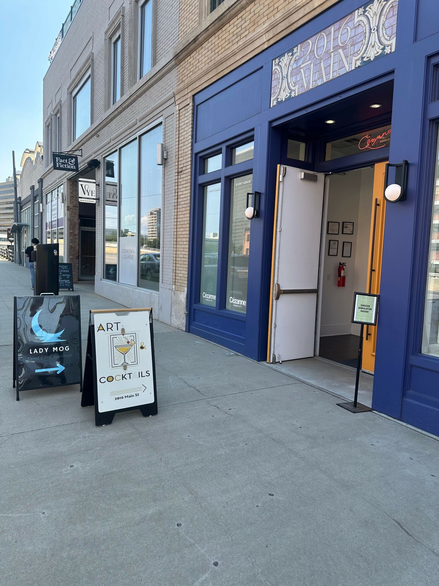 Blue storefront with an ATM and a white sandwich board sign outside on a sidewalk.