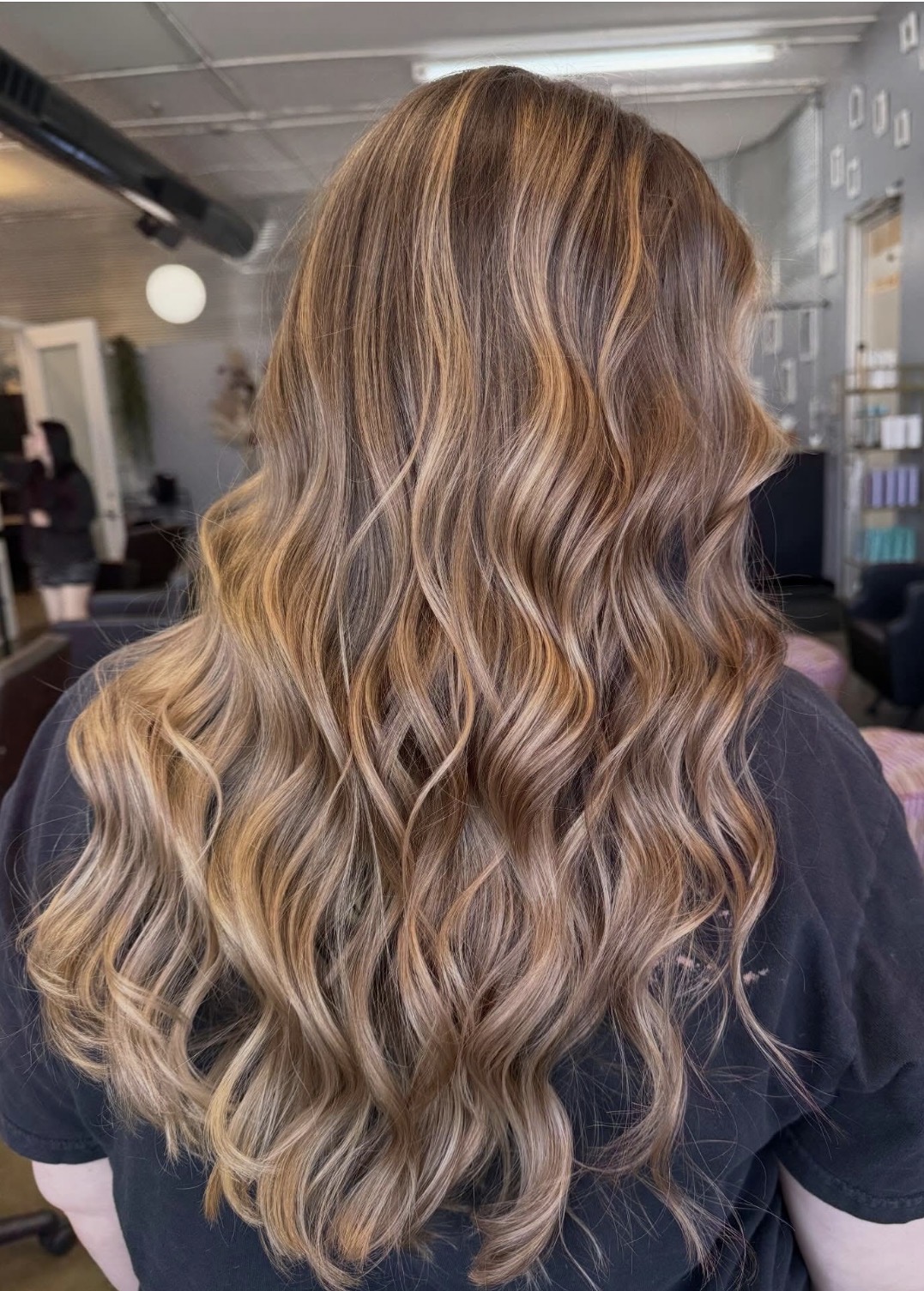Long wavy hair with blonde highlights, viewed from the back in an indoor setting.
