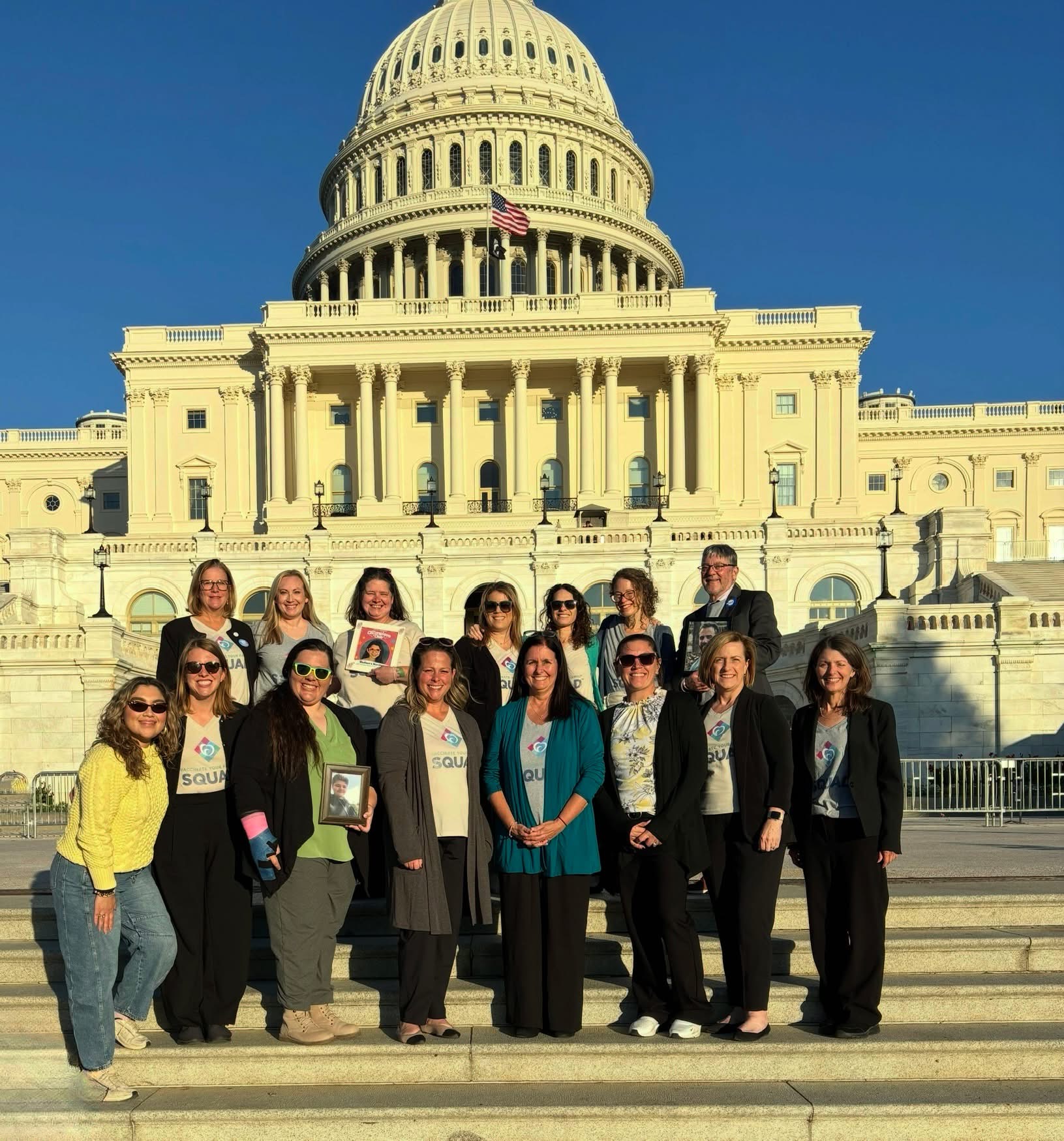 Group of people standing on steps in front of the U.S. Capitol building, sunny day, clear blue sky.