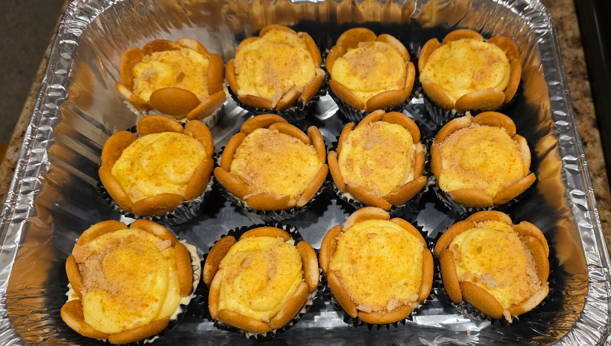 Tray of twelve baked egg muffins in paper cups on a baking sheet.