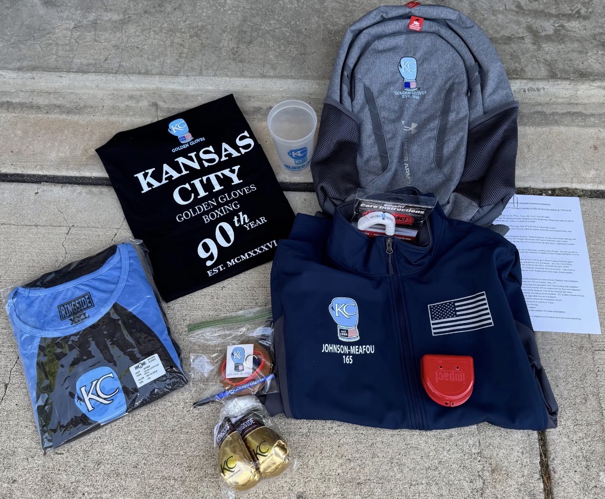 Collection of Kansas City Chiefs items including a backpack, clothing, and memorabilia on concrete surface.