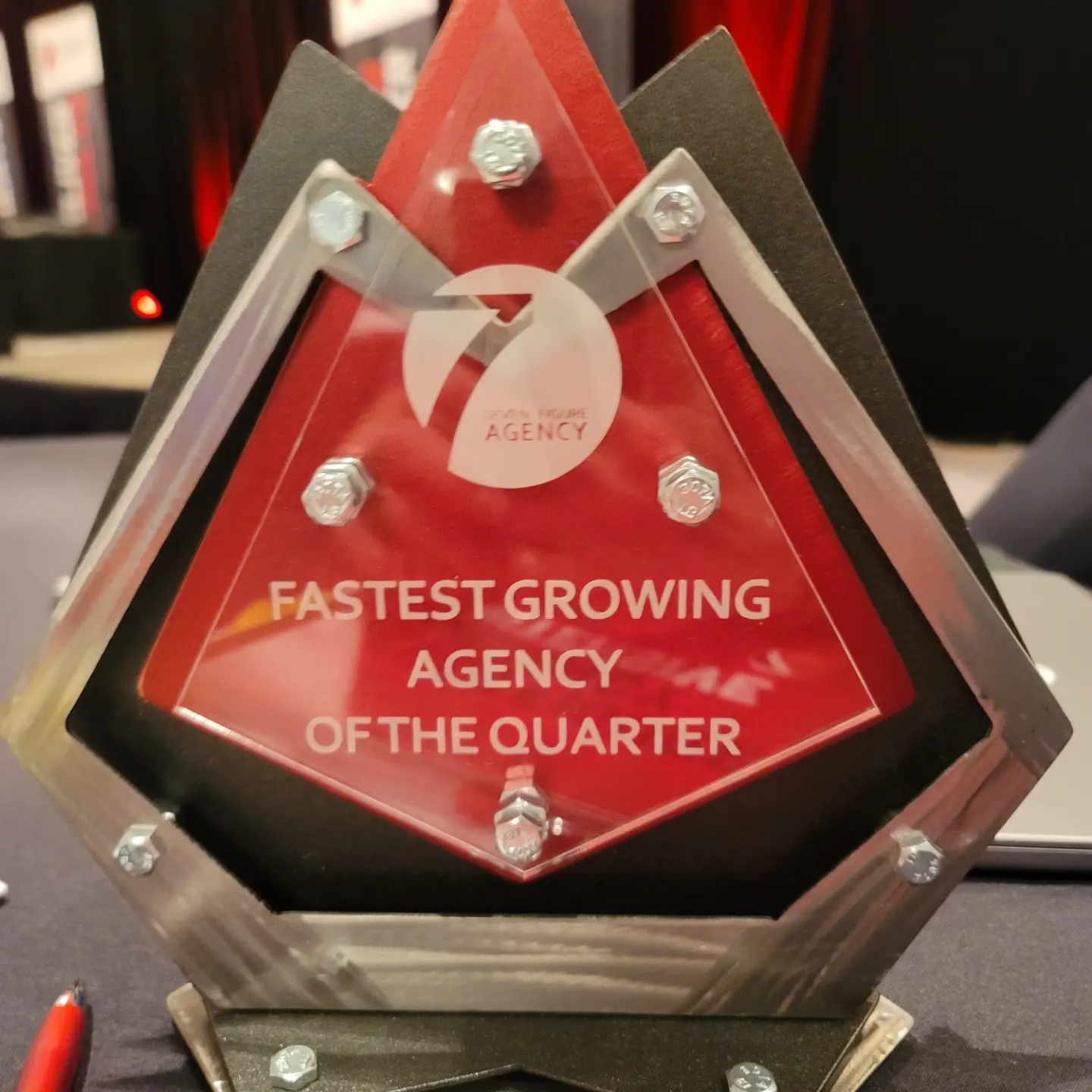 Triangular award with text: 'Fastest Growing Agency of the Quarter' and a circular logo, mounted on a black base.