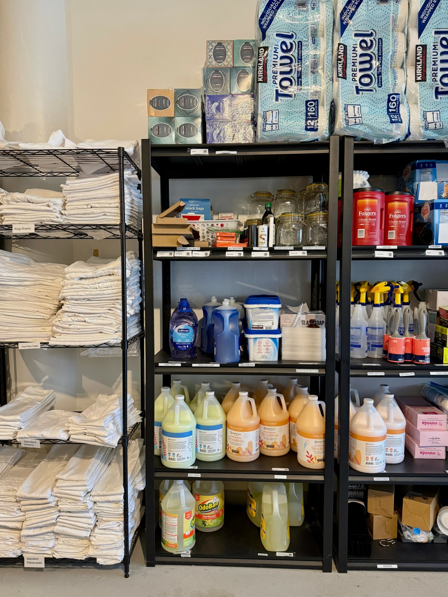 Shelves with paper, bottled water, cleaning supplies, and other household items in a storage room.