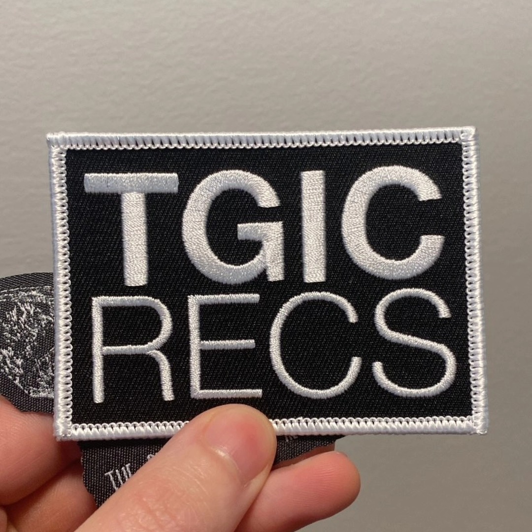 Patch with black background and white embroidered text reading 'TGIC RECS'.