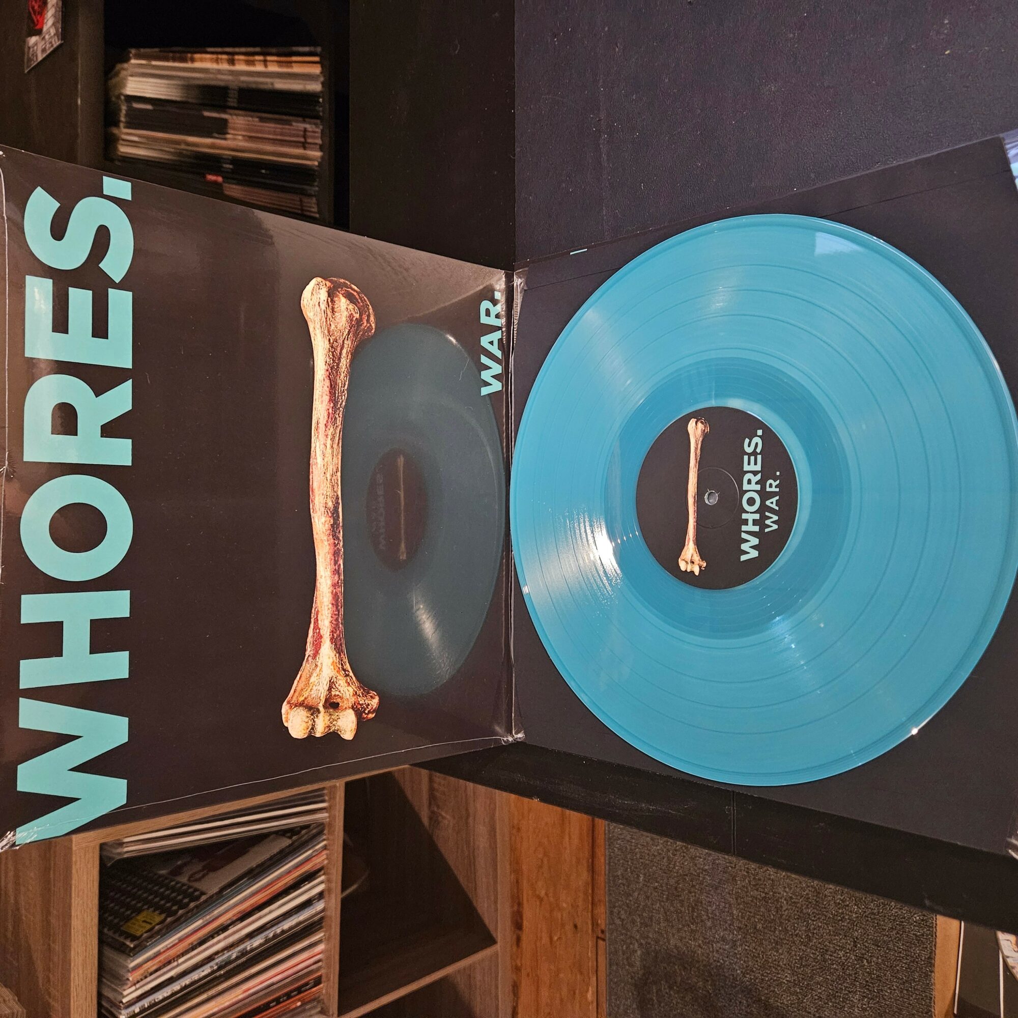 Blue vinyl record with black label, inside a black sleeve with text, and a bone illustration on the cover.